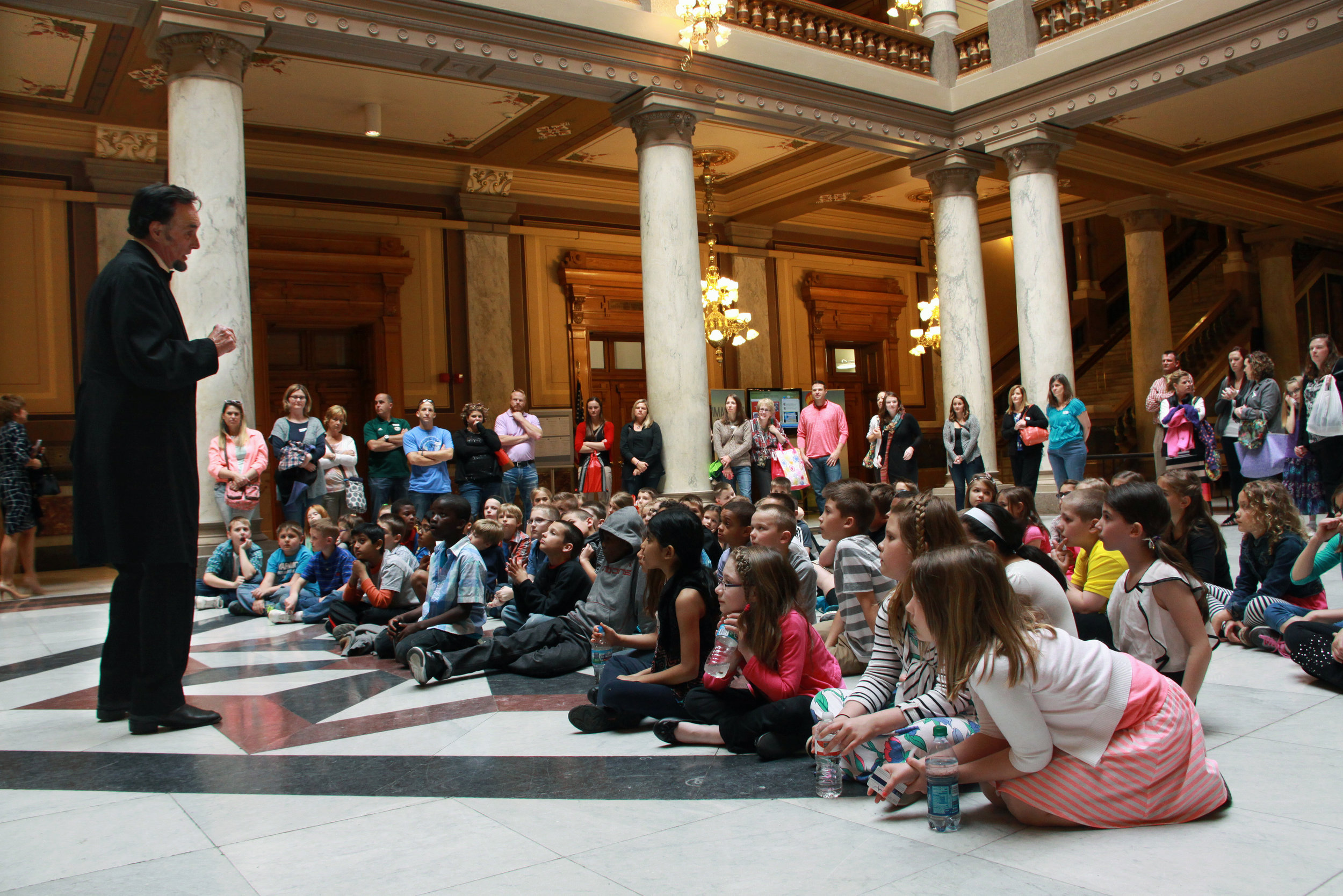 Children listen to President Abraham Lincoln reenactor in a courthouse lobby