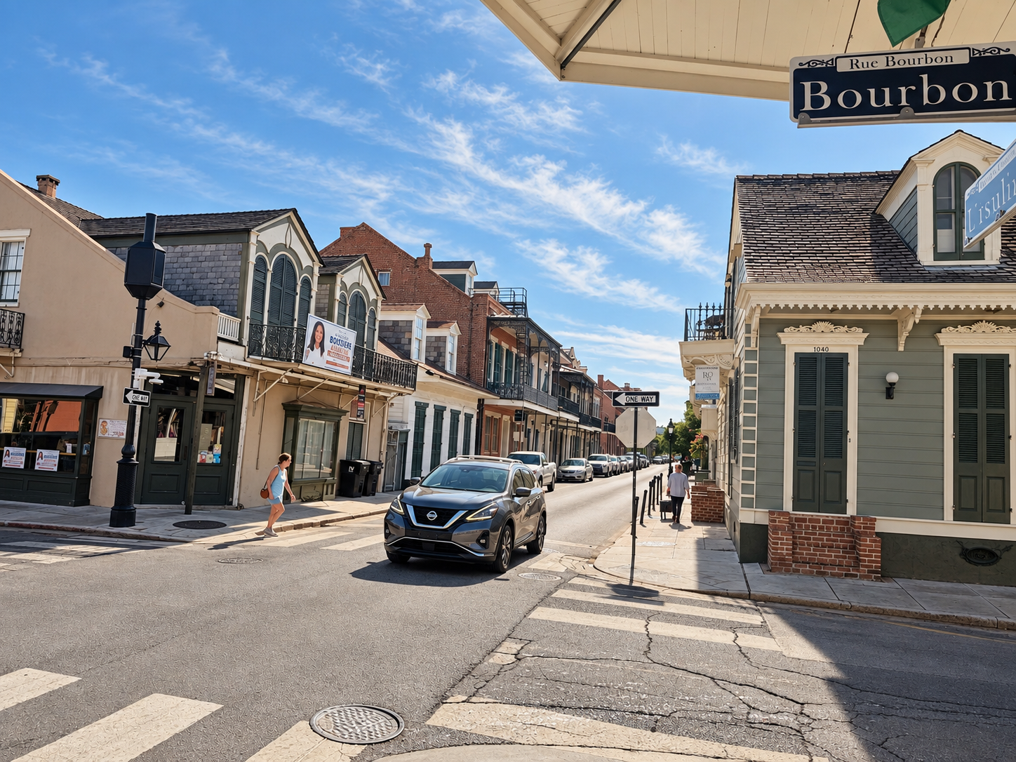 Bourbon Street at Saint Philip, with historic French Quarter balconies and shutters in warm daylight.