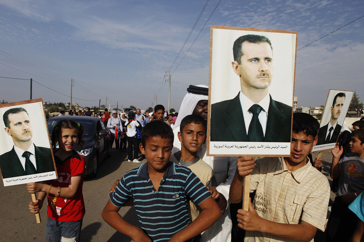 15 Children hold placards of President Asad, to welcome foreigners under supervision from state police, Darra, Syria. jpg