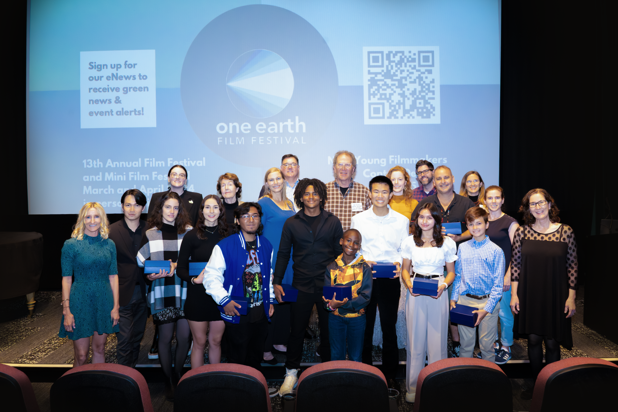 young filmmaker winners with environmental organization representatives in a theater with their trophies
