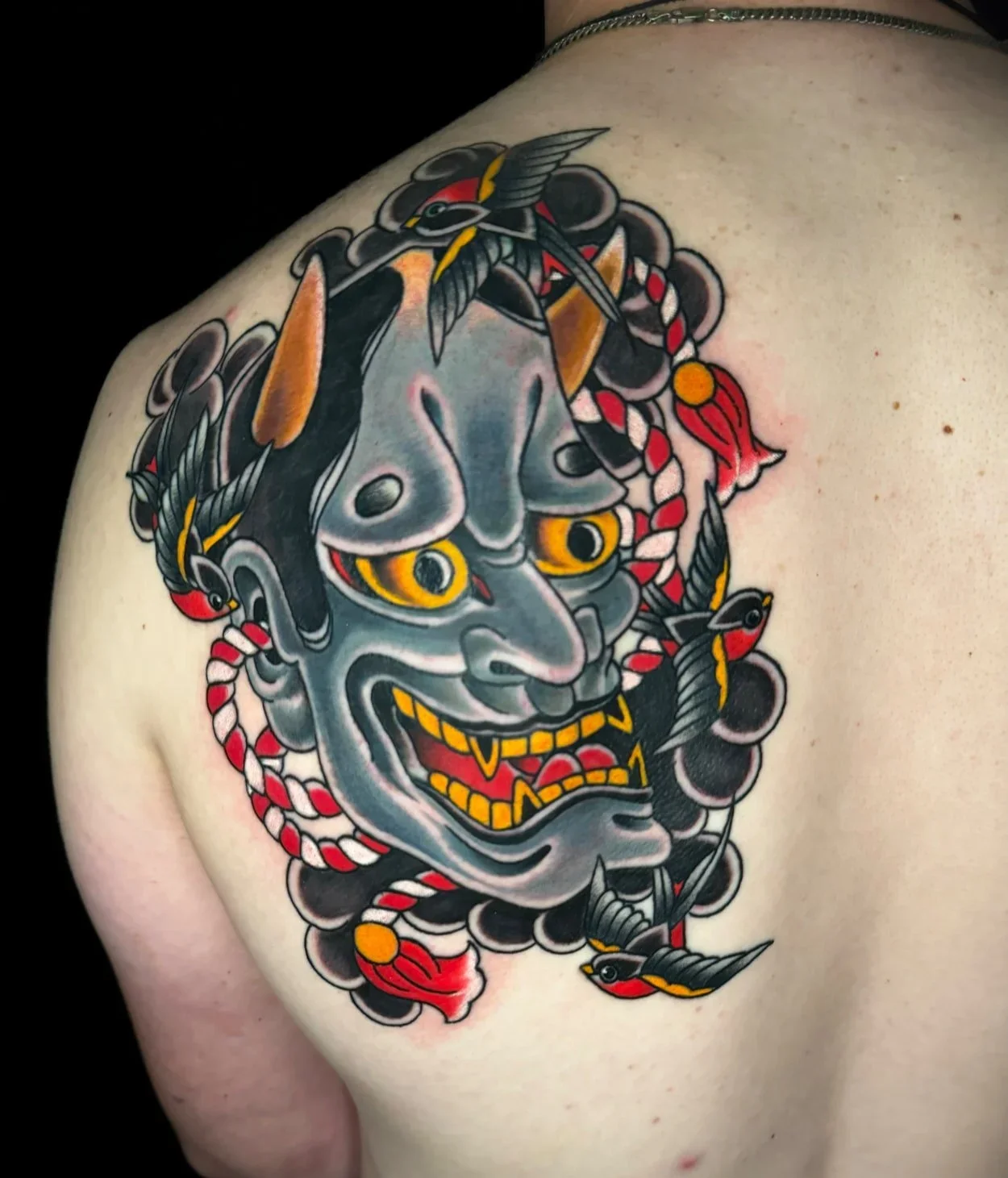 Hannya mask and swallows back tattoo blending Japanese and American traditional styles, by Chris Cockrill in San Diego
