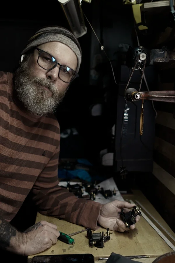 Chris Cockrill building a handmade coil tattoo machine at his bench in San Diego