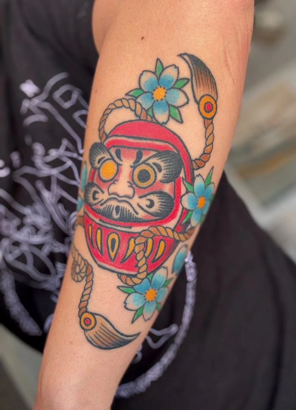 japanese Daruma doll tattoo on a forearm in color 
