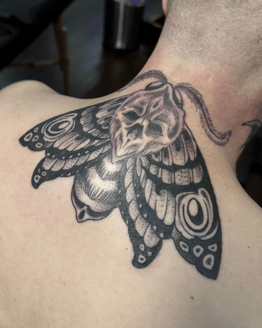 Bold black and grey death moth tattoo with dotwork shading on the upper back by Chris Cockrill