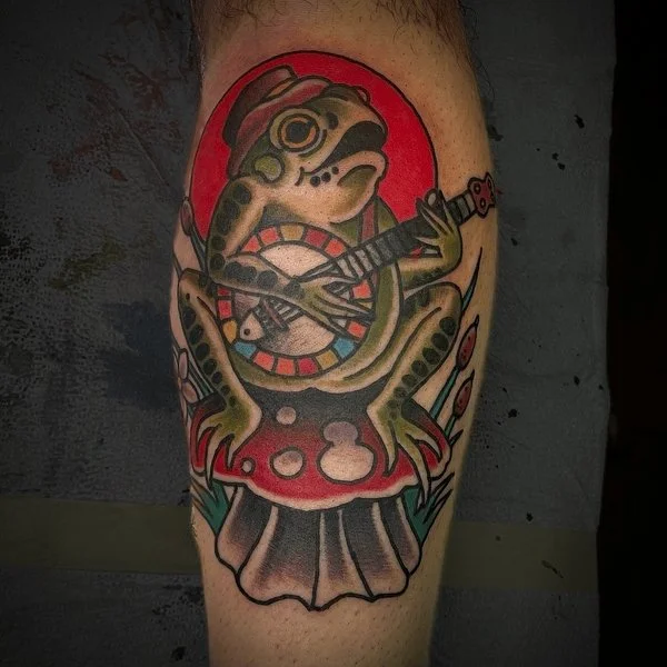old timey traditional frog tattoo playing a banjo 