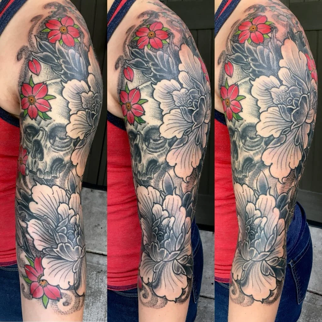 A tattoo sleeve featuring large white peony flowers with detailed shading, interspersed with pink and red flowers with green leaves, all on a person's arm.