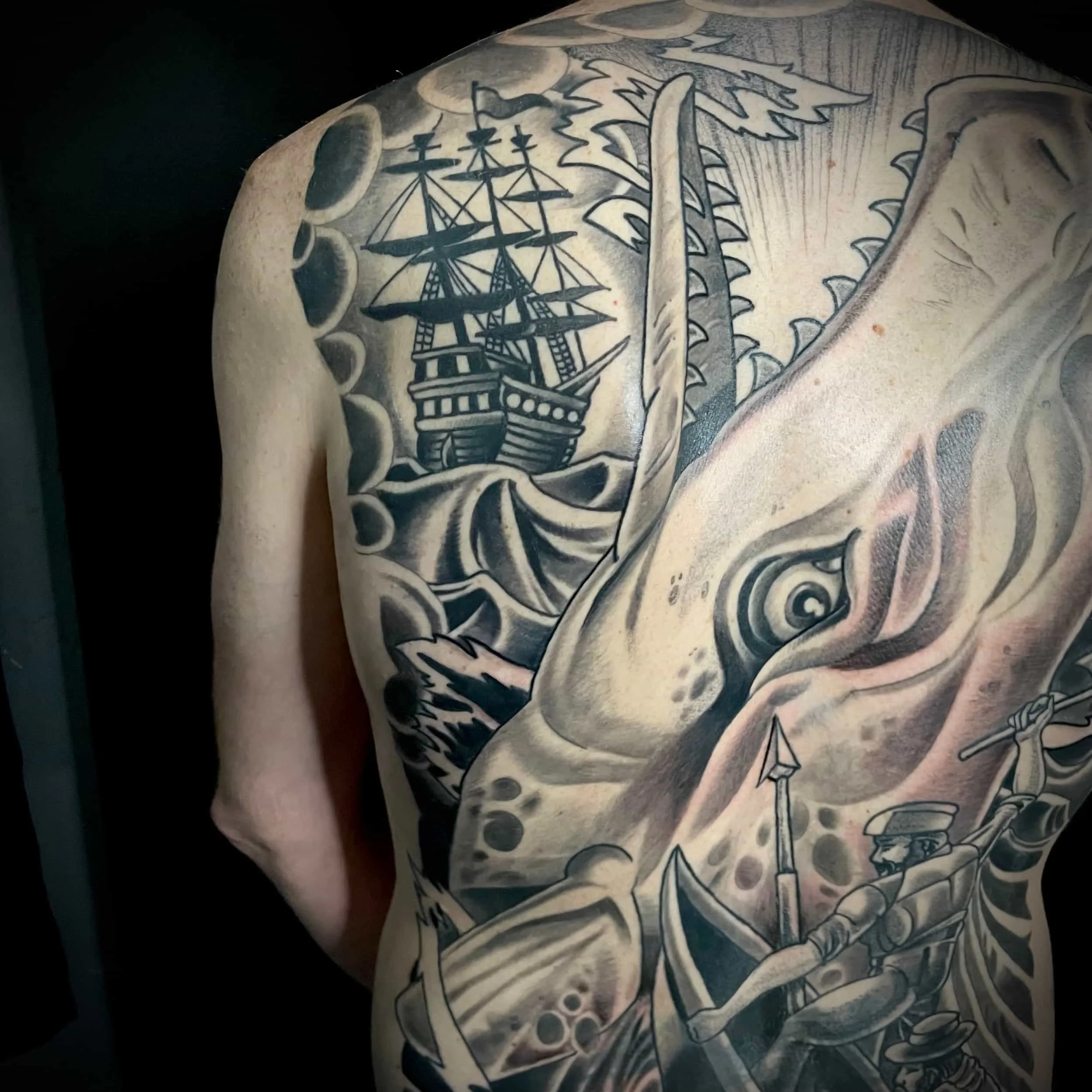 Black and gray ship and whale back piece tattoo by San Diego tattoo artist Chris Cockrill