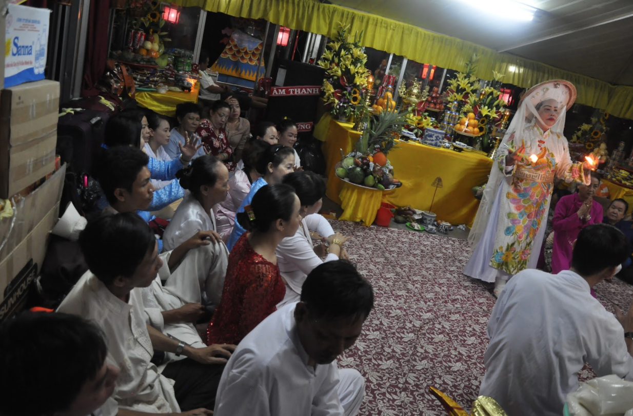Practitioner Kim Chi performs a lên đồng ritual for her temple delegation on a boat at the Điện Hòn Chén festival. (Photo: Loa/Jenny Lý) 