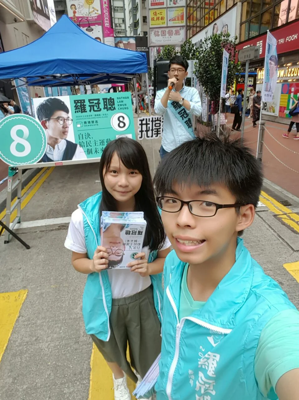 Agnes Chow Ting (left) and Joshua Wong (right) on the street campaigning for Demosisto’s Chairman, Nathan Law (back). (Photo: Facebook/Joshua Wong)