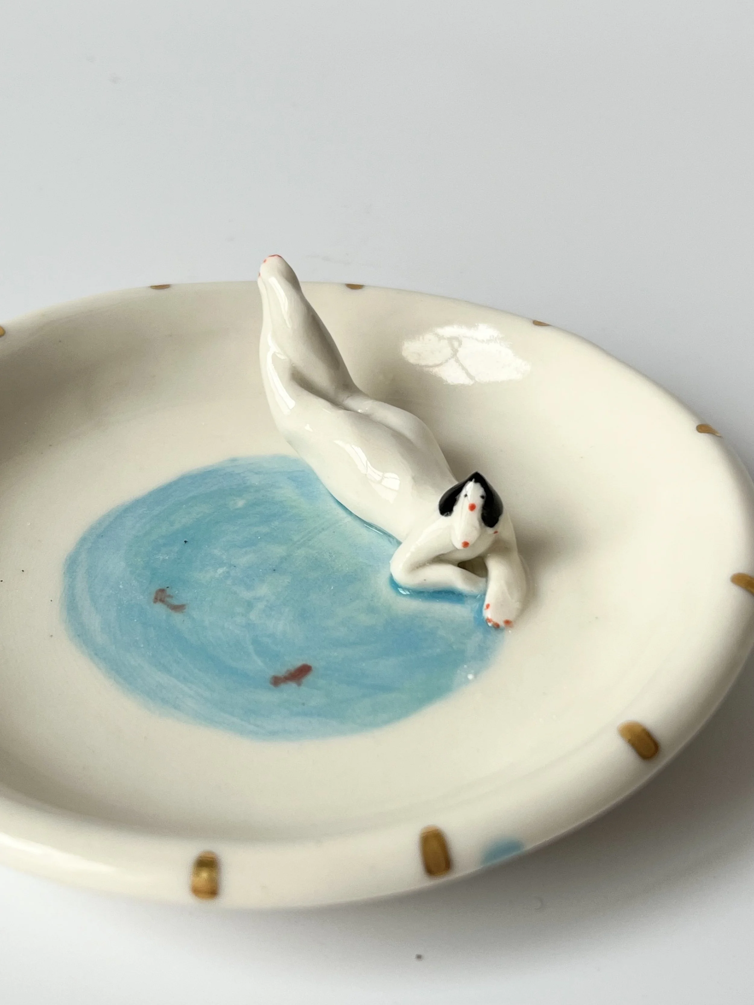 Small trinket dish with a tiny figurerealxing by a lake
