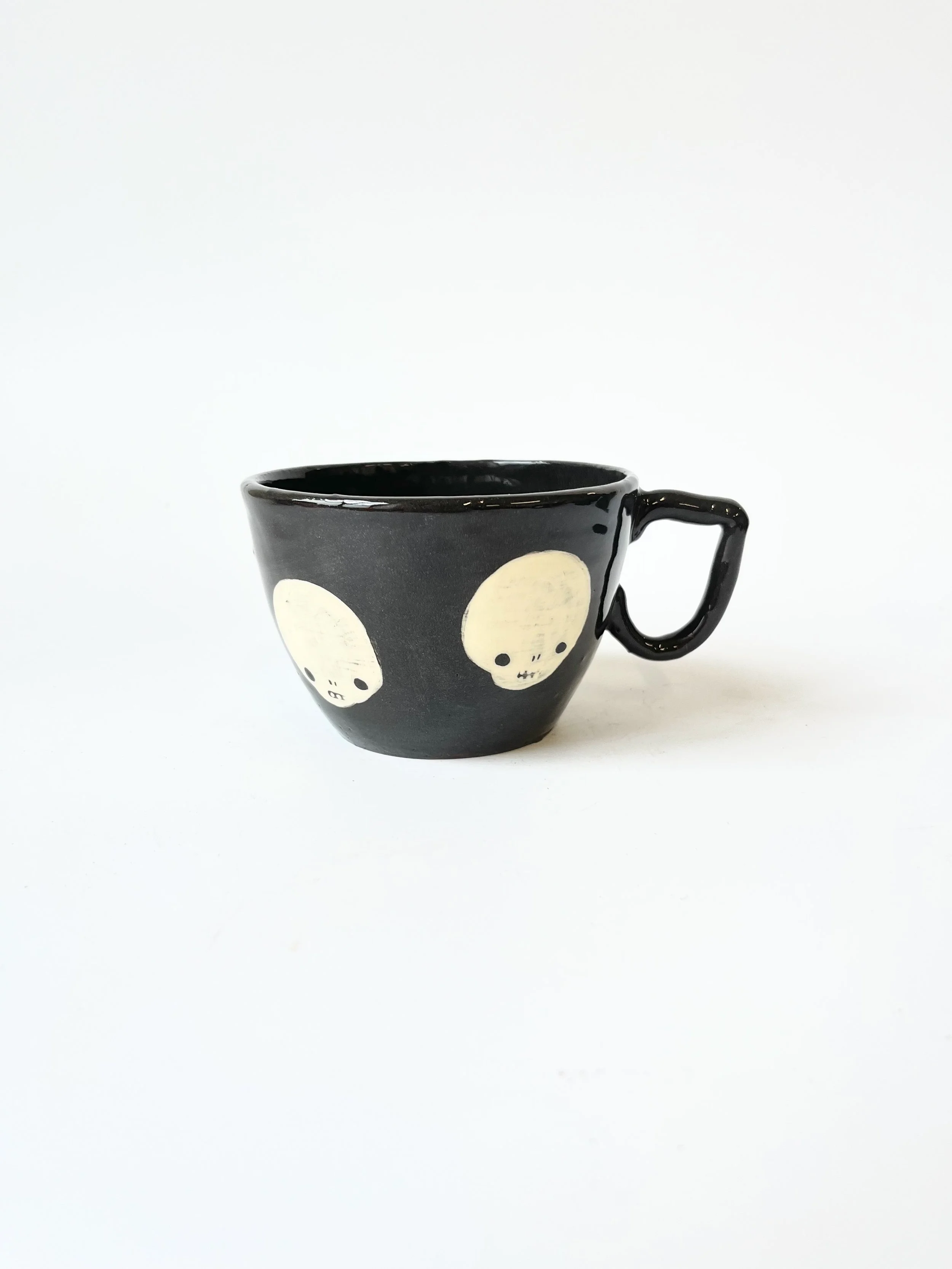 Black earthenware cup with skulls and a very fancy handle
