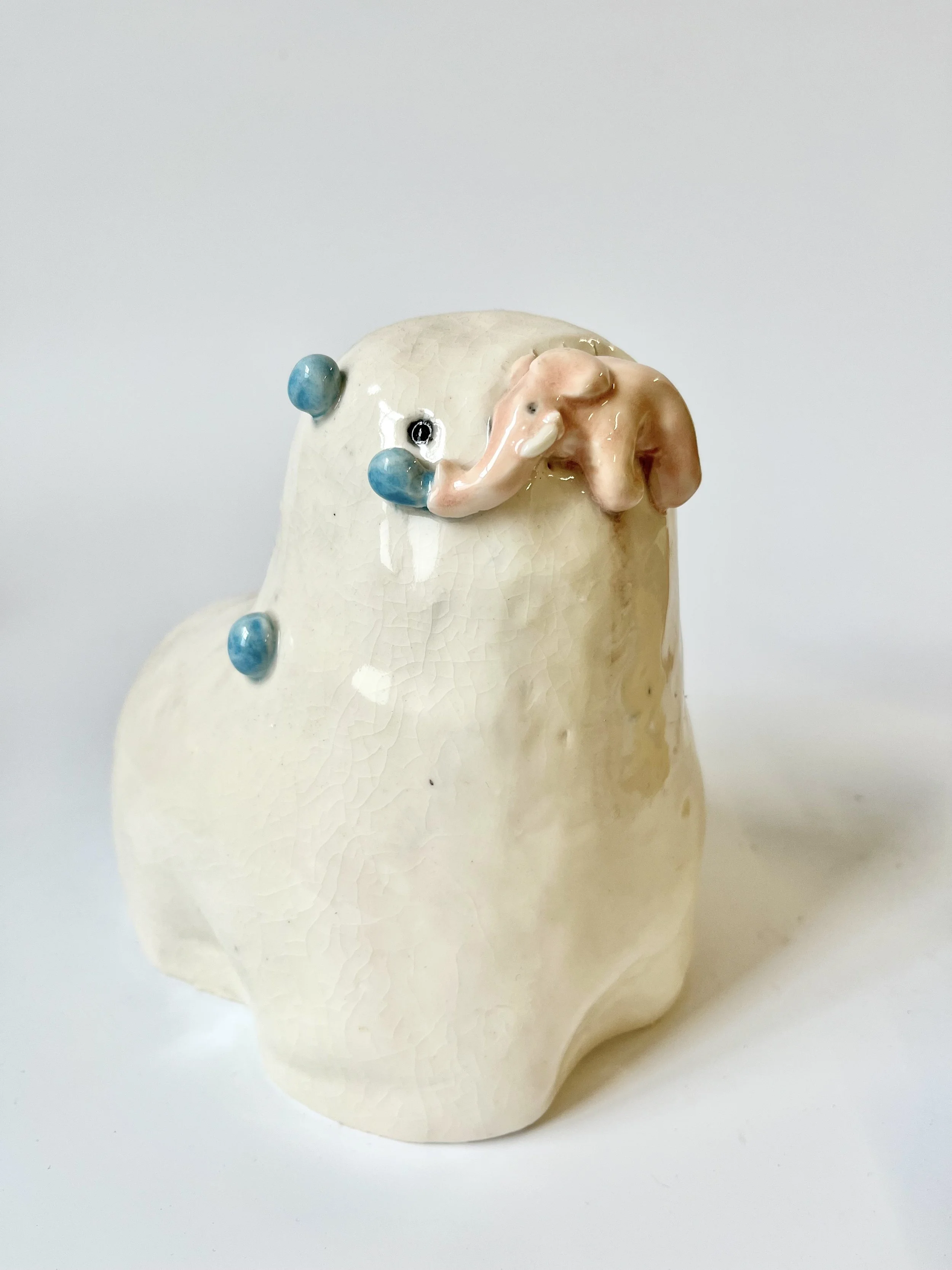 White porcelain teethie, holding a little pink elephant in its mouth