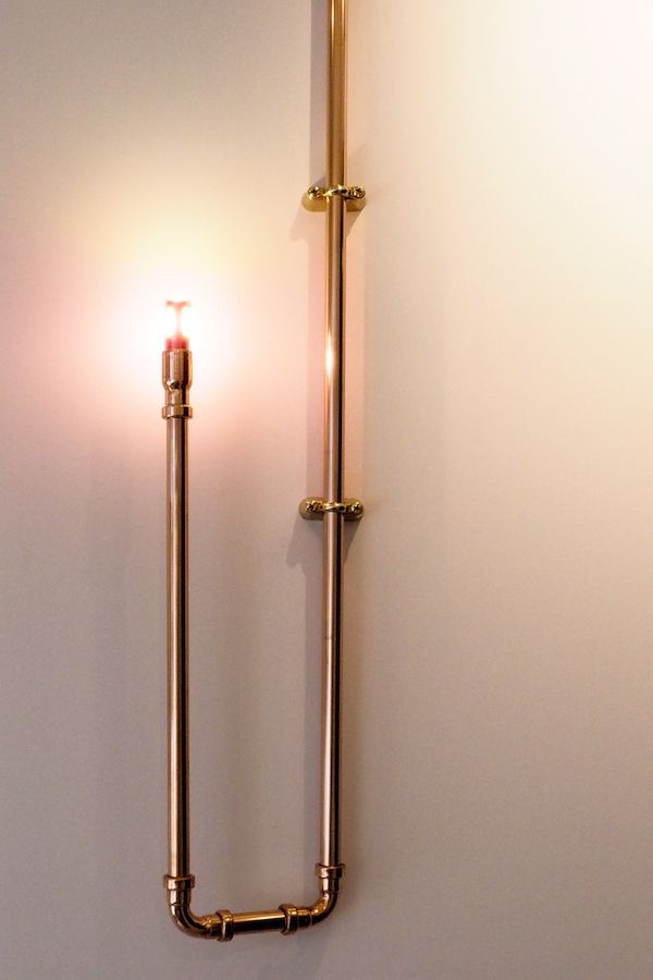 pale pink walls from little greene paints are illuminated by dog's body copper piping as a candelabra