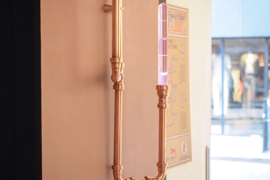 a close up of dog's body copper pipework as a candelabra, against mid-toned pink walls from little greene paint co
