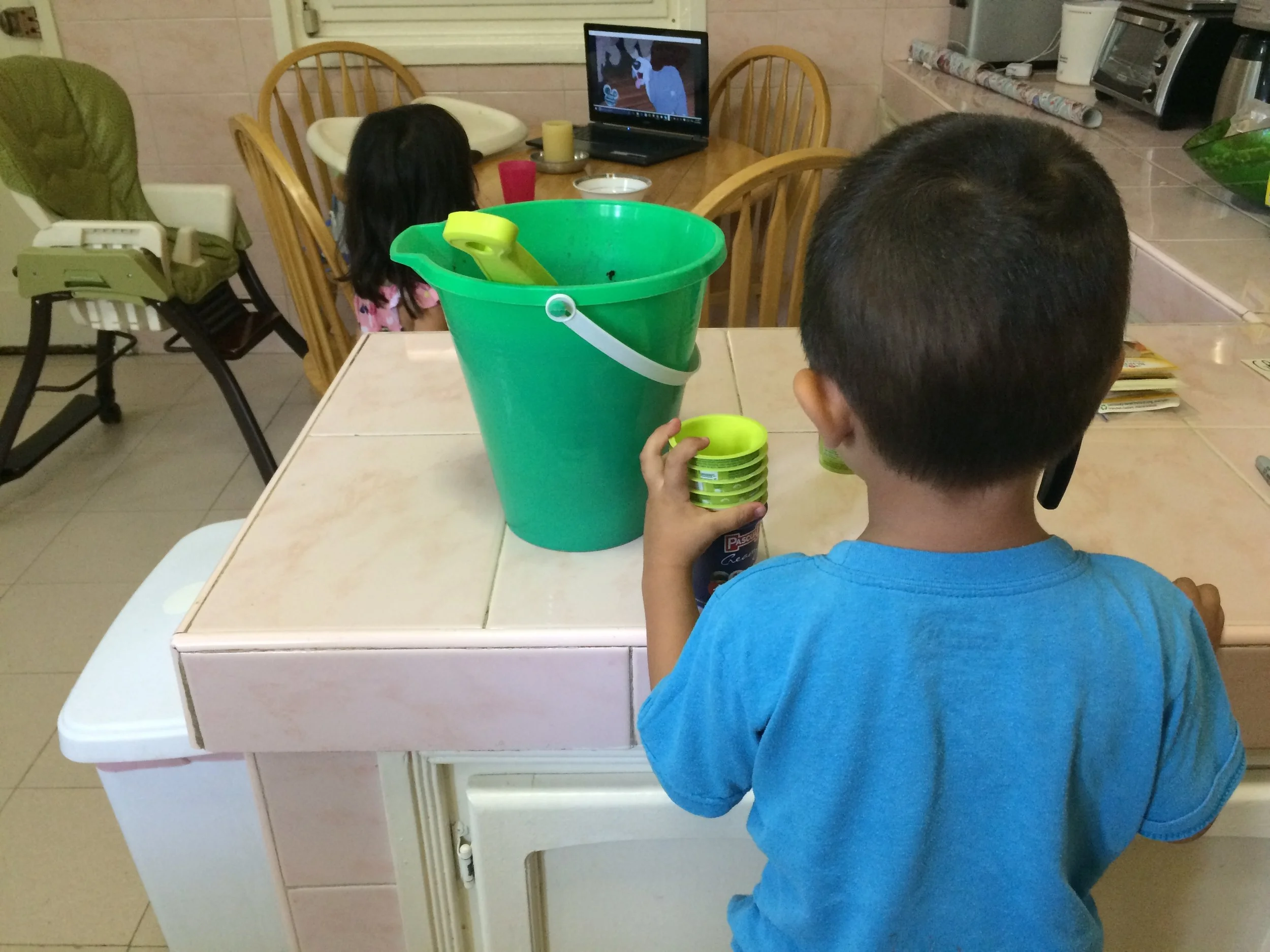 My kids helping me plant seeds in our kitchen while watching The Little Mermaid in Spanish. 