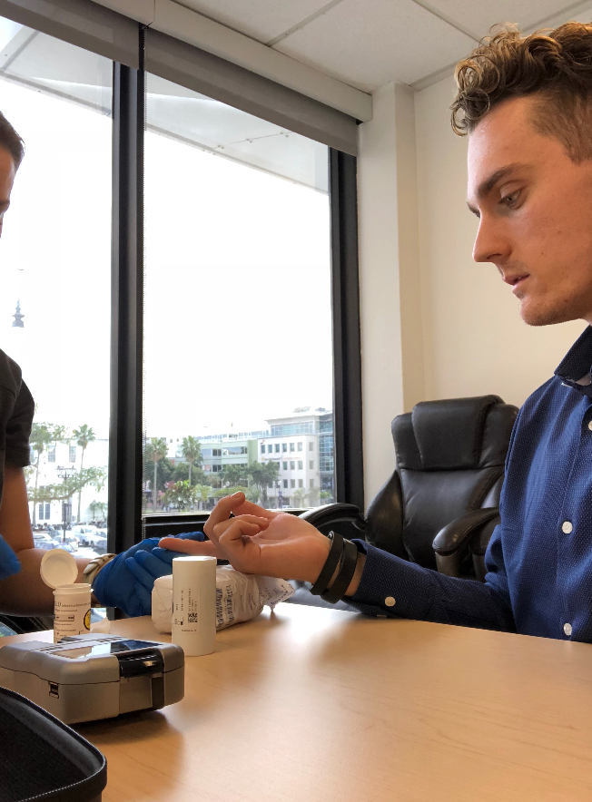 A Registered Nurse performs a finger prick sample to measure lipid profile and glucose.