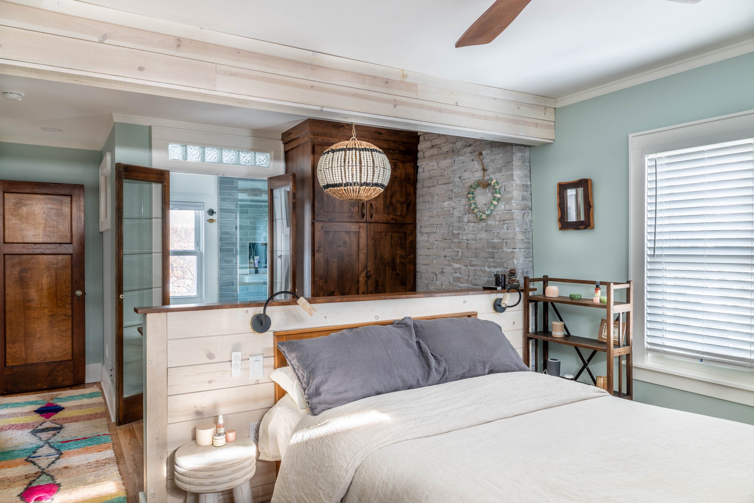 Light blue green bedroom sutie with exposed brick, alder cabinetry, and shiplap headboard