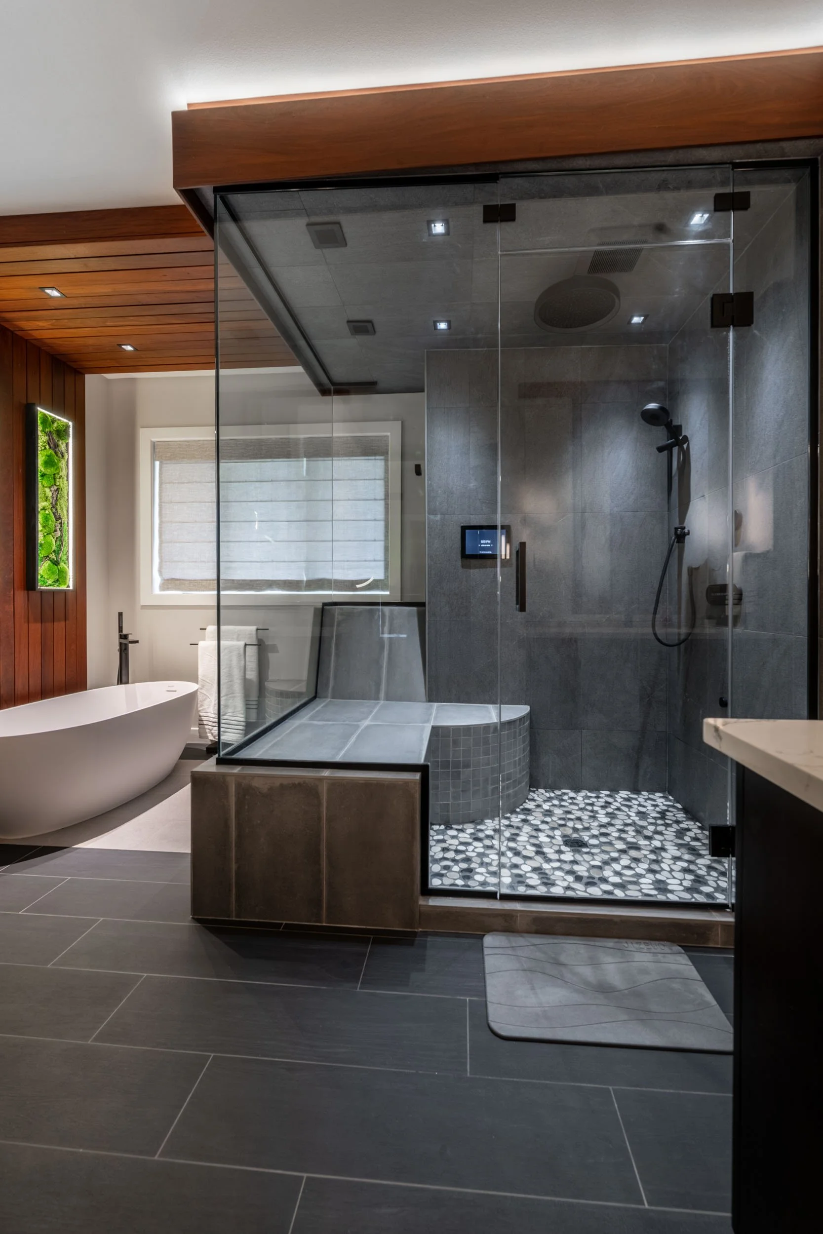 A view of the first thing you see when walking into the bathroom: the shower, bathtub, teak accents, and aesthetic lighting
