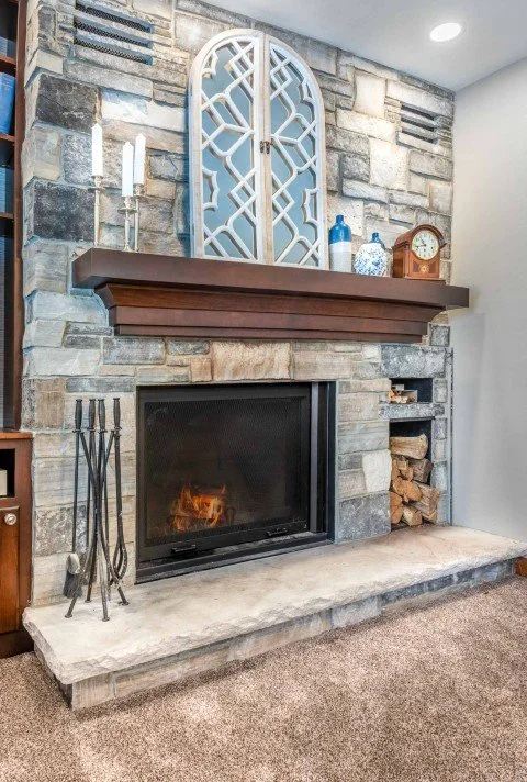 Custom wood burning fireplace in a remodeled family room with firewood storage