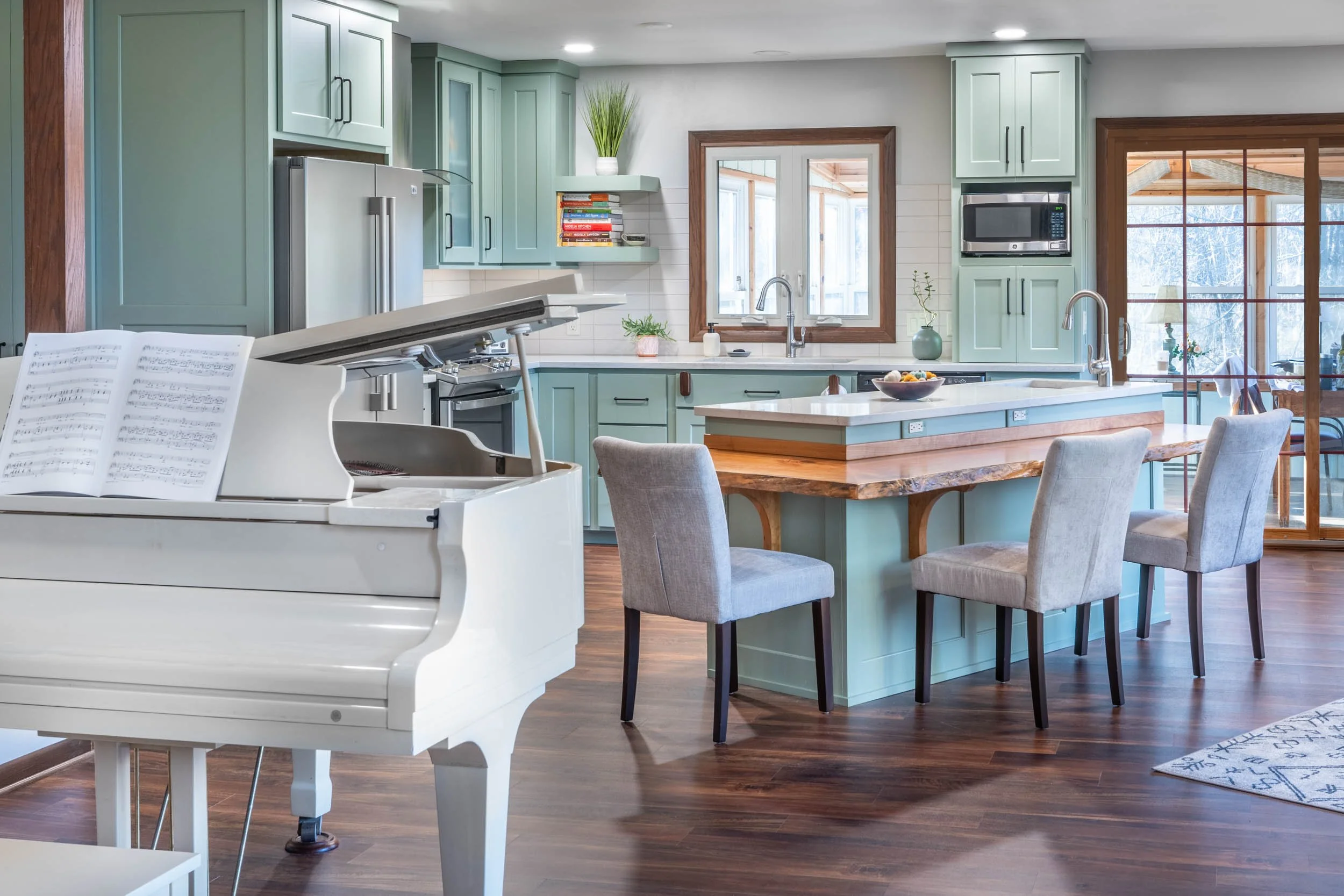 light green kitchen cabinets with dark wood floors and a wood accent on the island countertop
