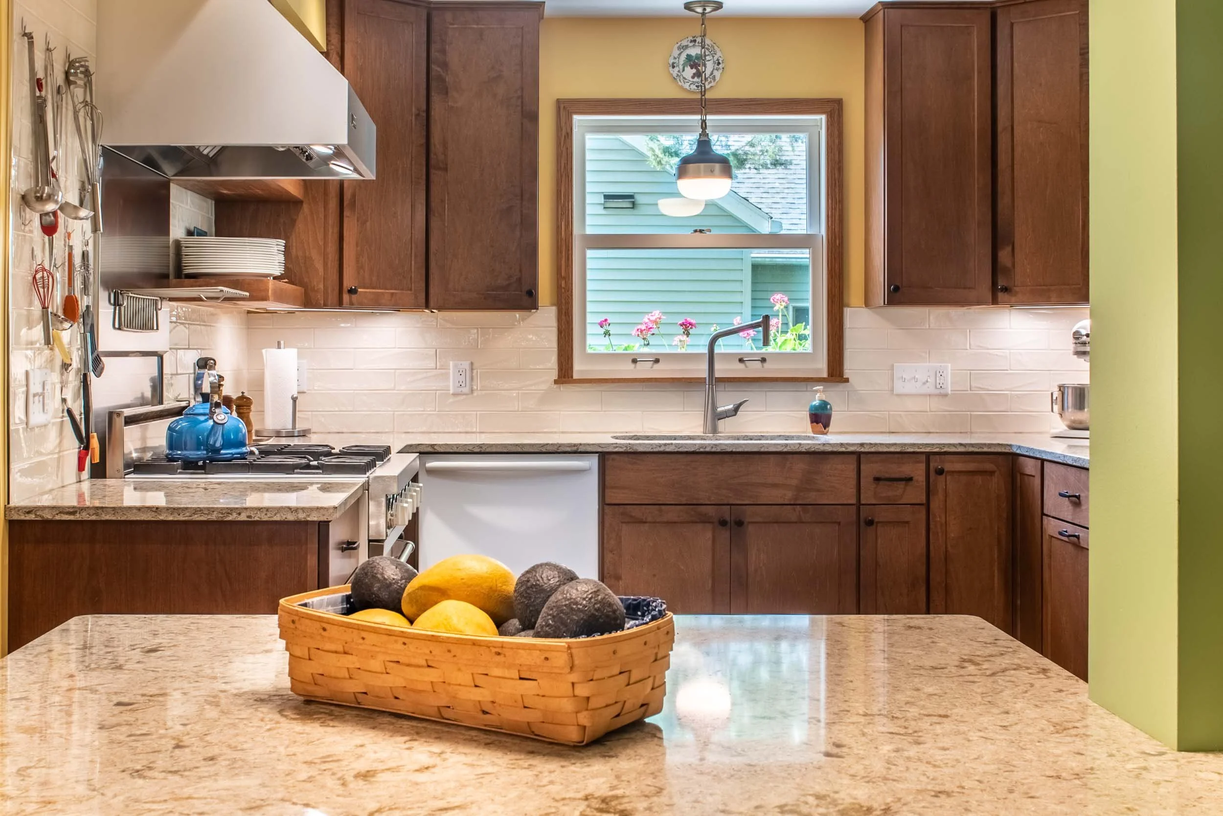 A remodeled kitchen with dark maple cabinets, white subway backsplash, and grey and white quartz countertops