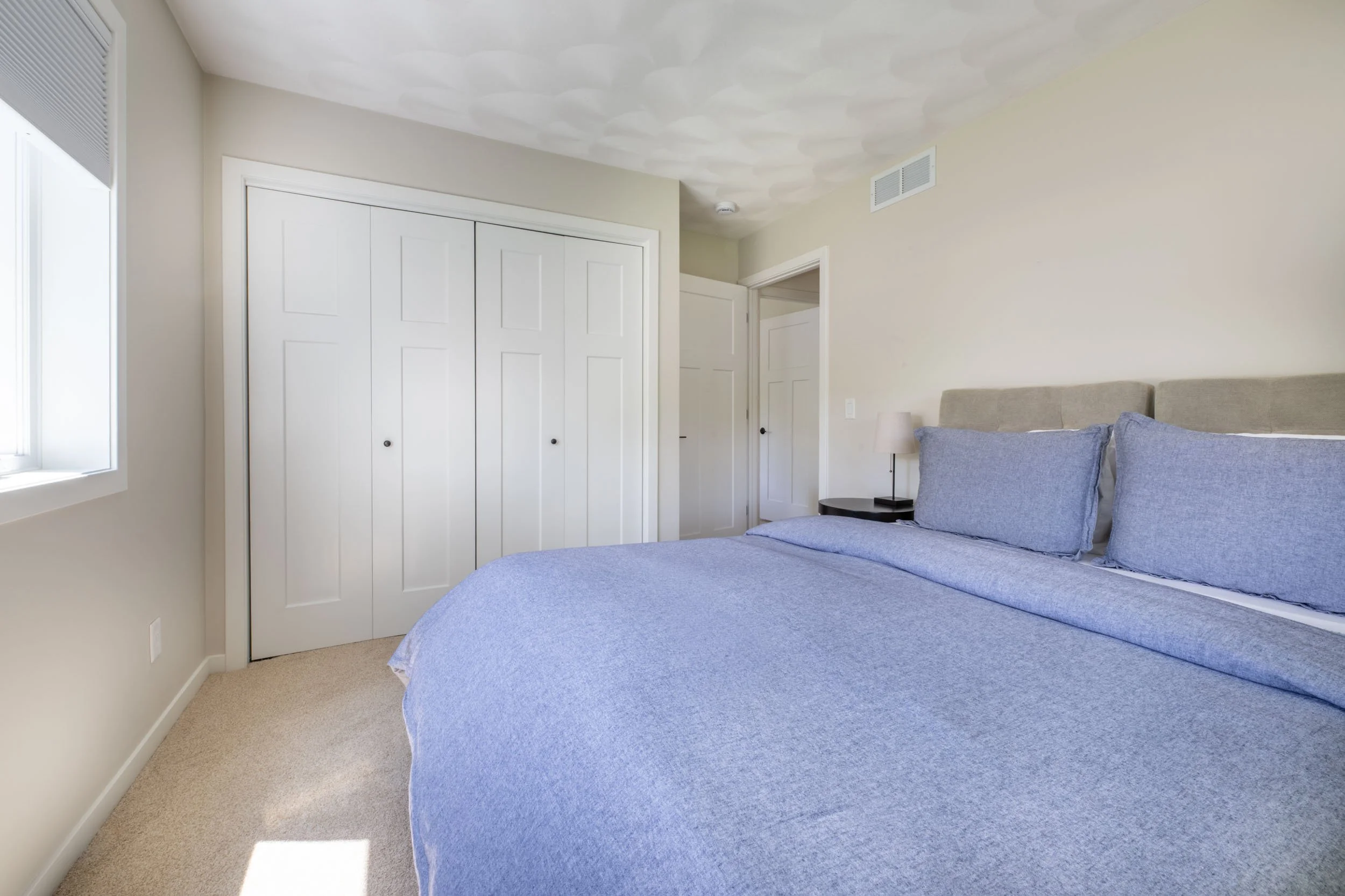 Overall view of the guest bedroom, highlighting the new carpet, base trim, window & casing, & new closet doors