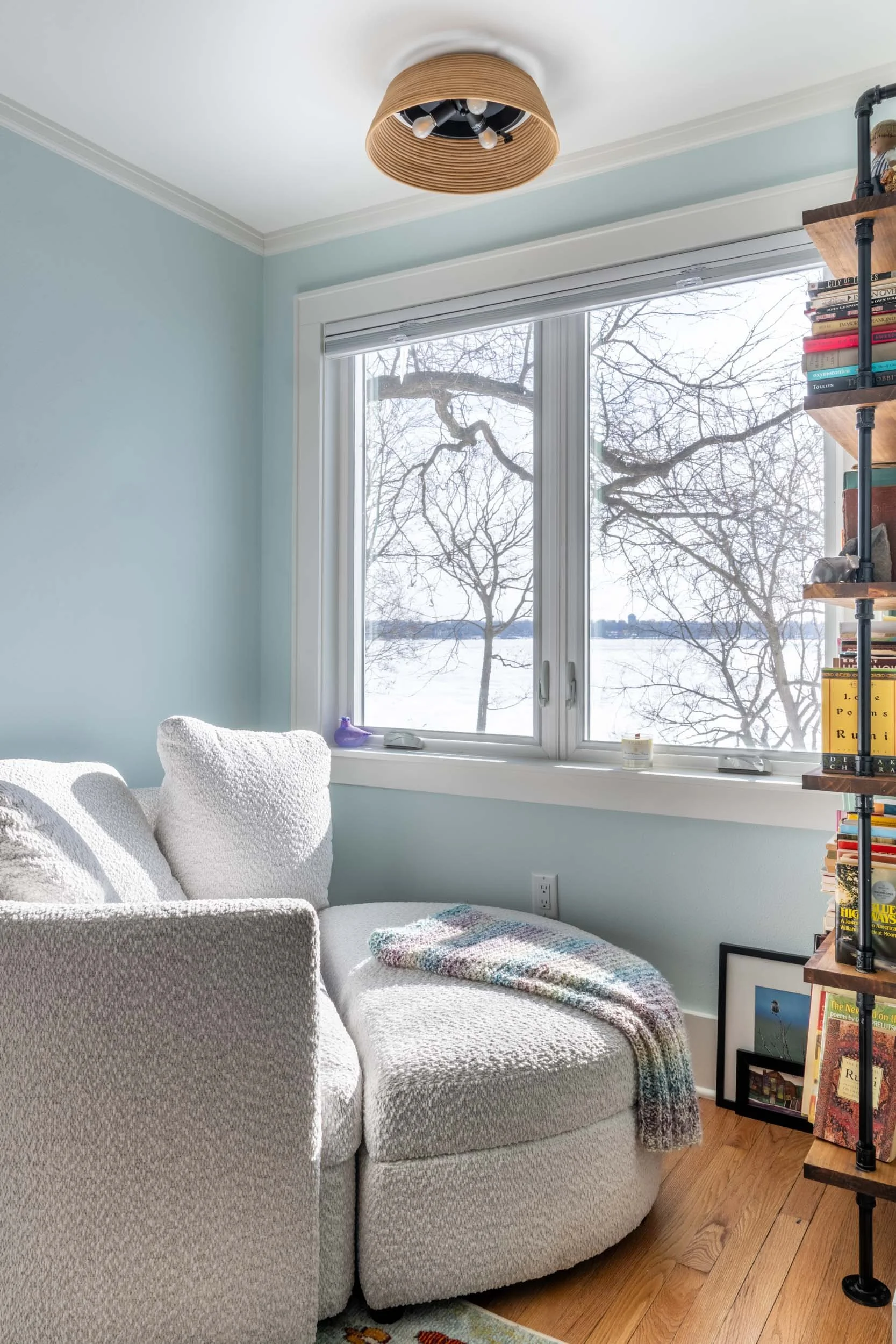 Image of the seating area with pipe and board bookcase and overstuffed chair and ottoman