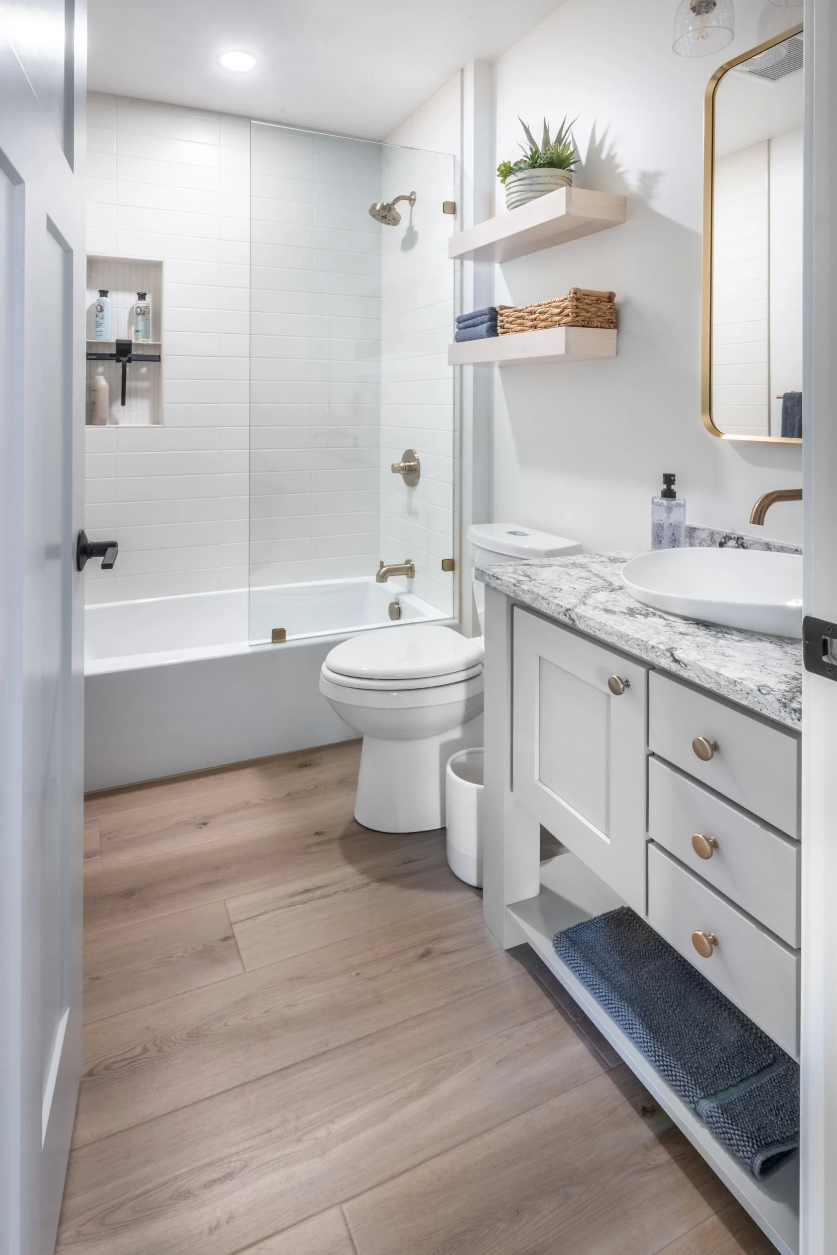 View into the guest bathroom, featuring the new vanity with a Cambria countertop, unique Kohler vessel sink, & Delta wall mounted faucet, new Kohler tub with a Daltile tile surround, Delta shower fixtures, a Miseno toilet, Kohler mirror.