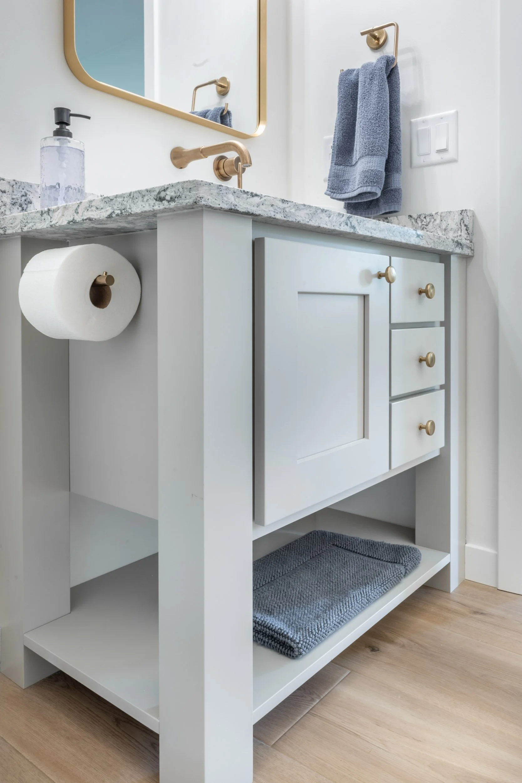 Close up view of the vanity, looking up, showcasing the bottom storage shelf & ‘freestanding inspired’ design