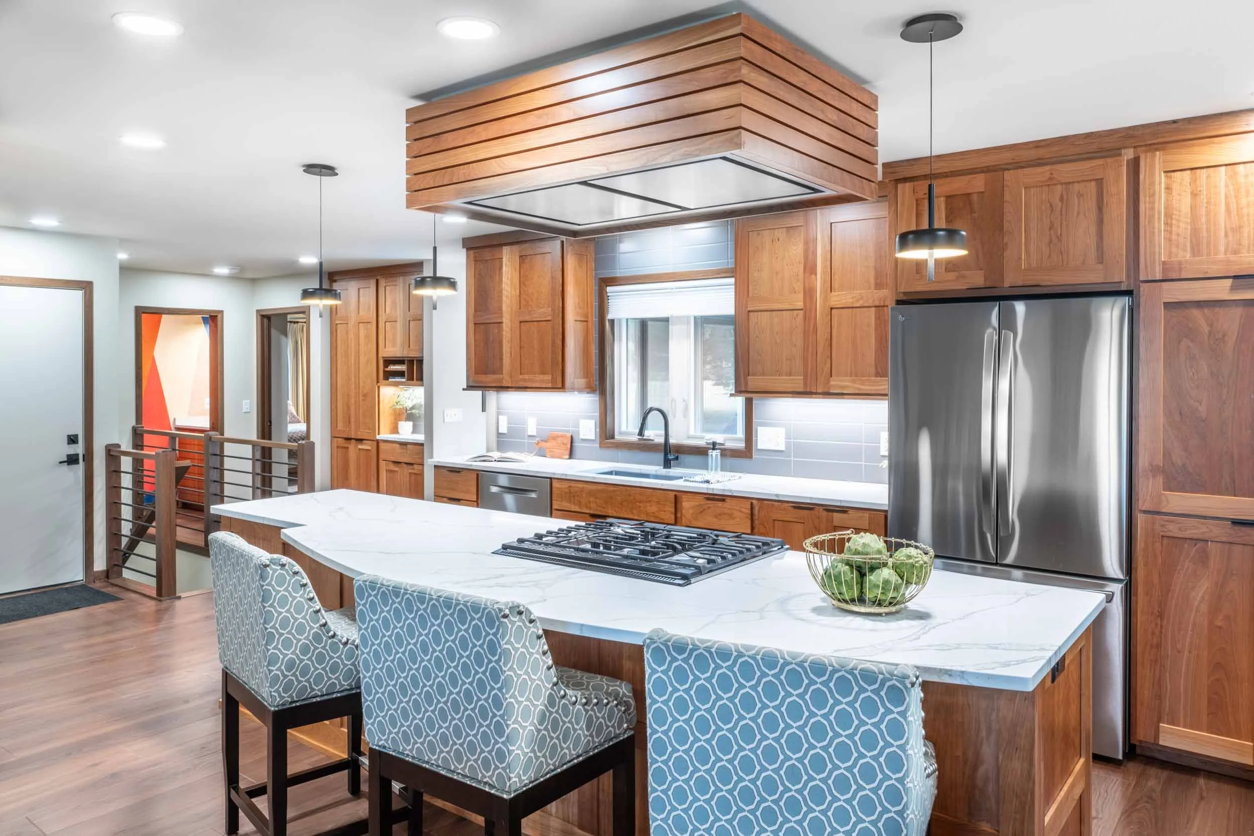A midcentury ranch home with cherry cabinets, cooktop in the island, and a cherry cloud range hood.