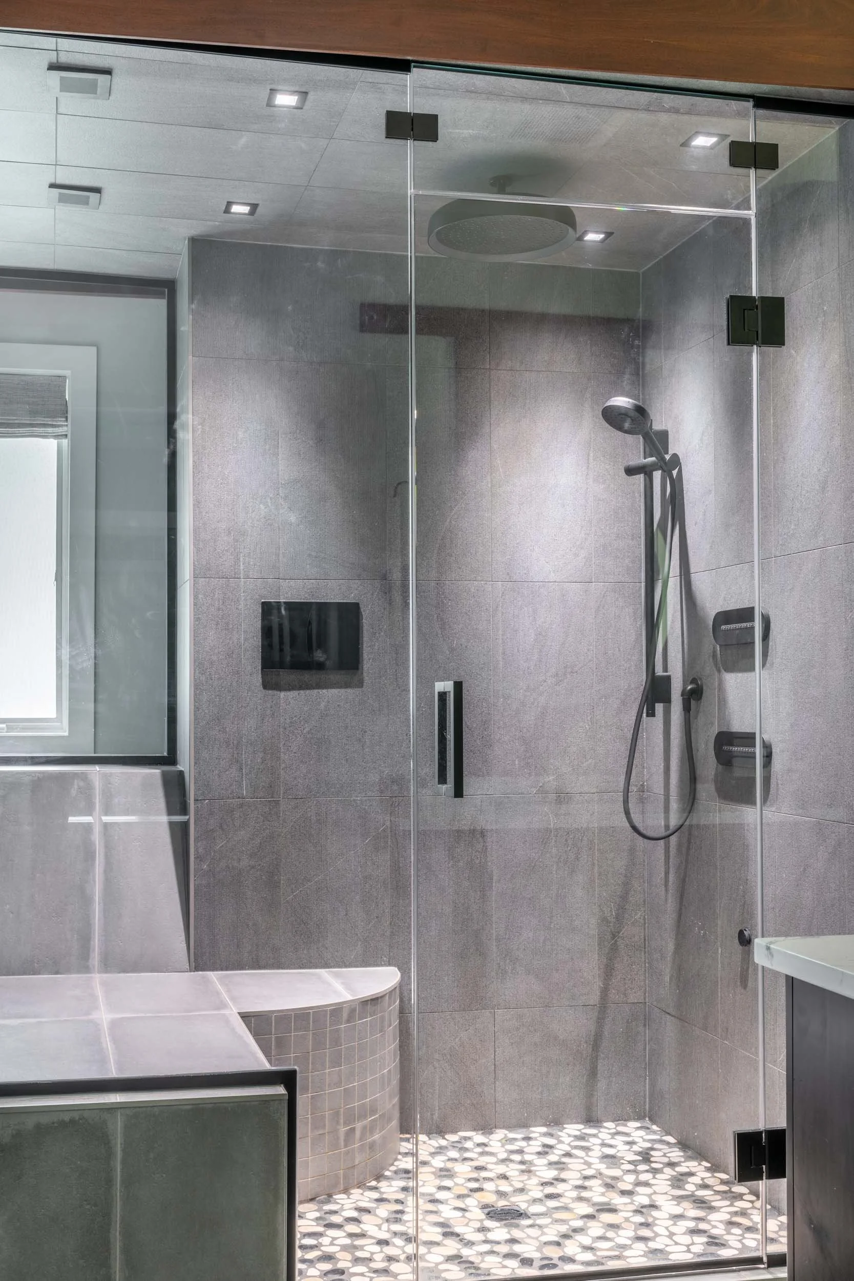 View of the shower showing the glass door and louver from the bathroom entrance