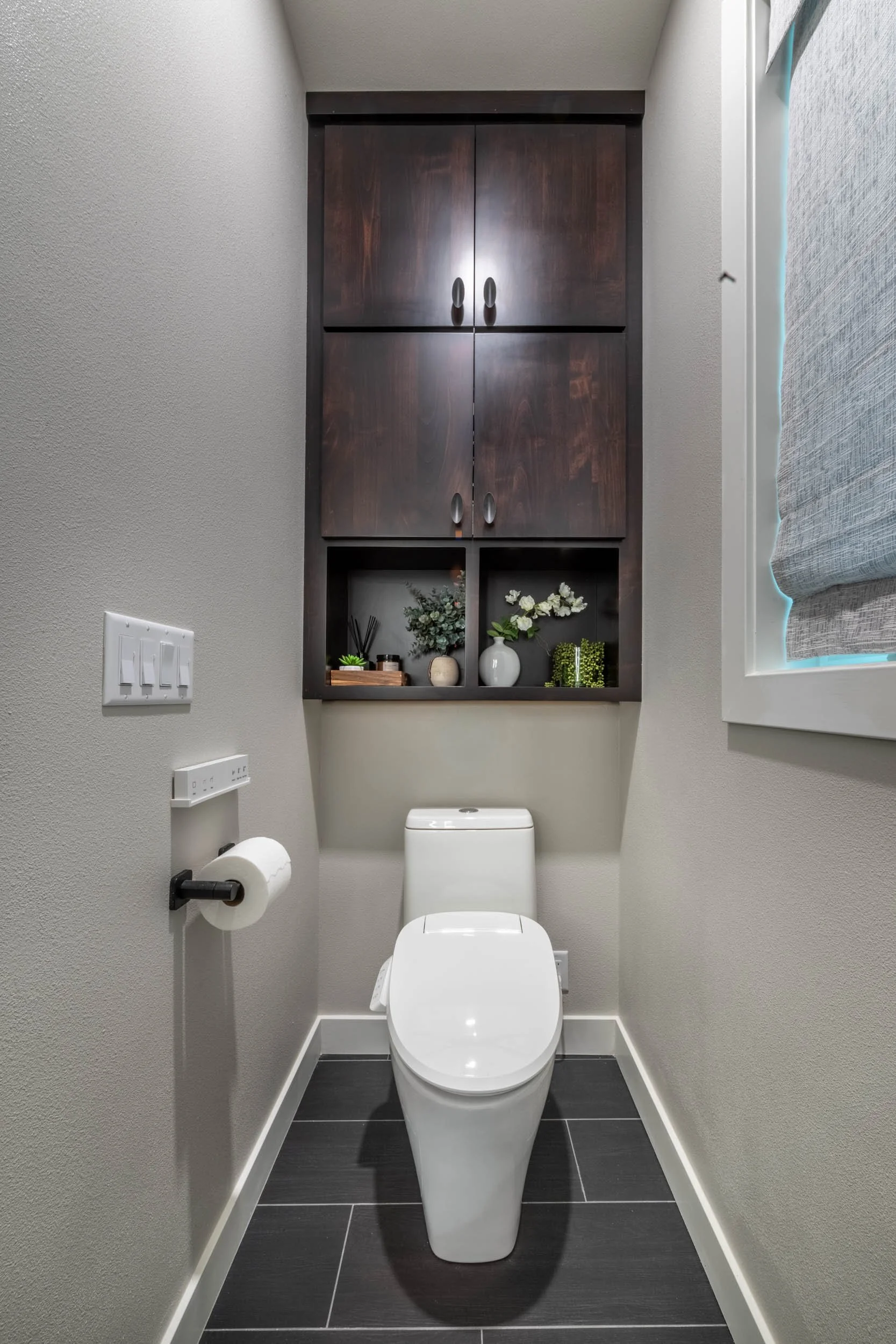 A wide-angle view of the toilet alcove featuring a Toto toilet and custom storage cabinet above