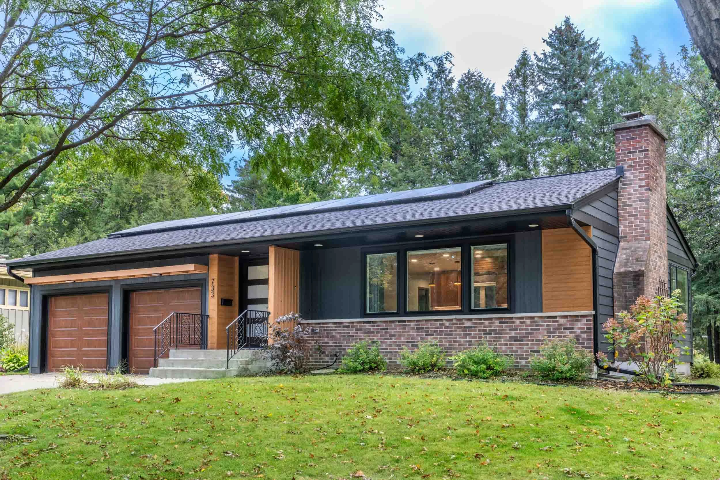 A ranch home with charcoal siding and wood accents
