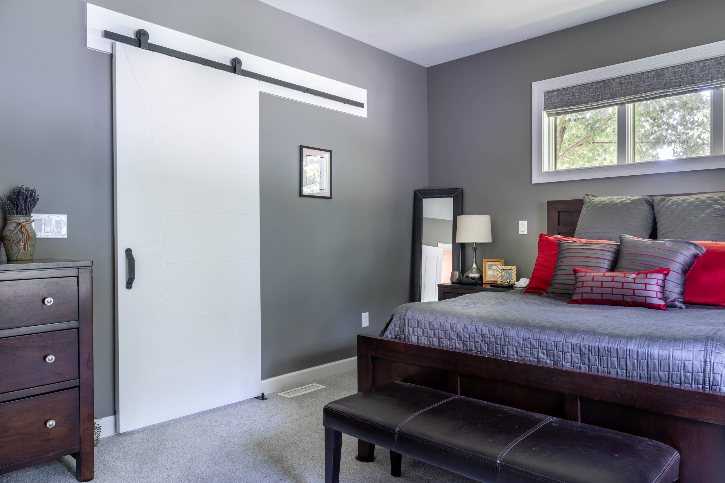 A wide-angle view of the bedroom walking into the bathroom featuring the custom barn door closed