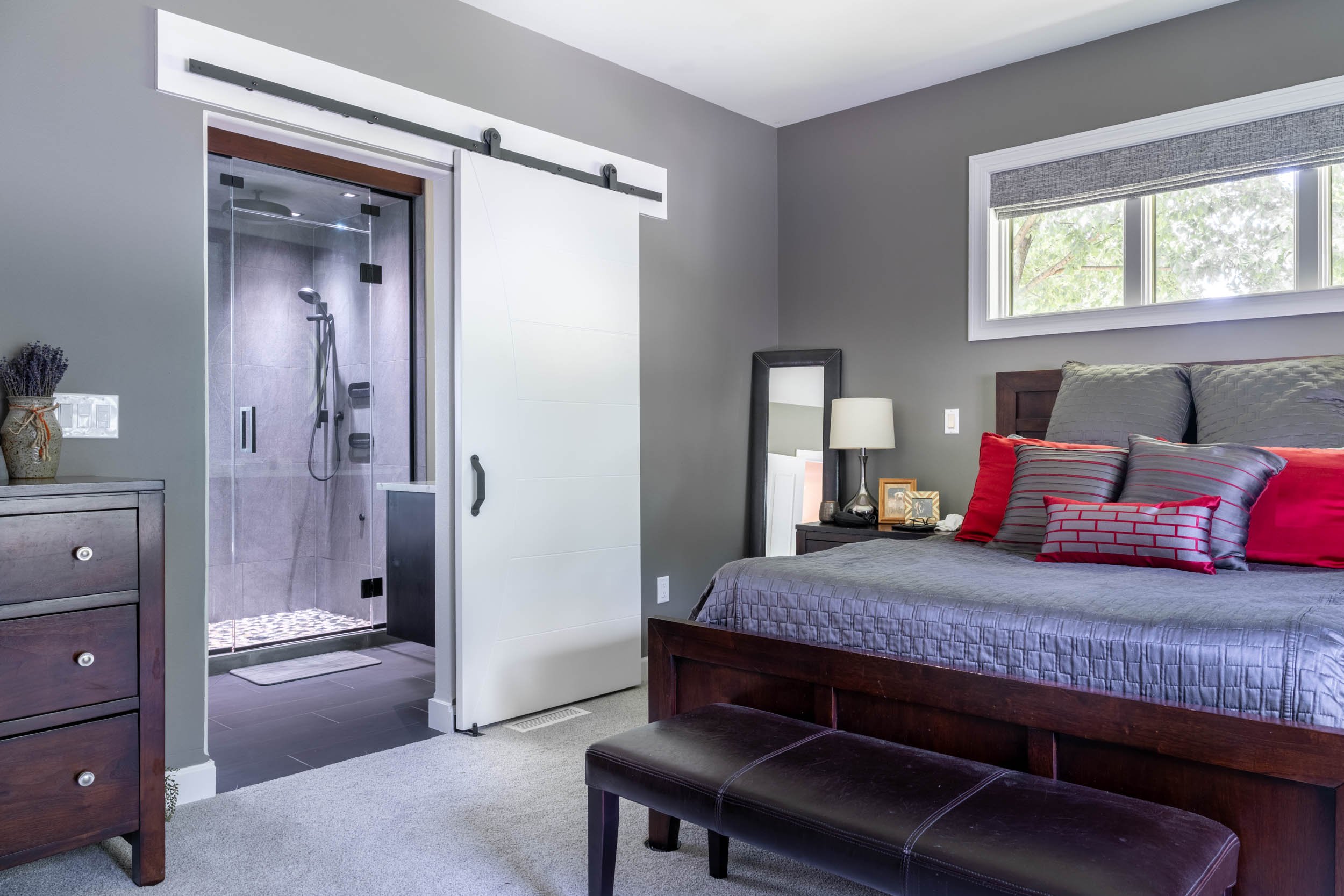 A wide-angle view of the bedroom walking into the bathroom featuring the custom barn door open