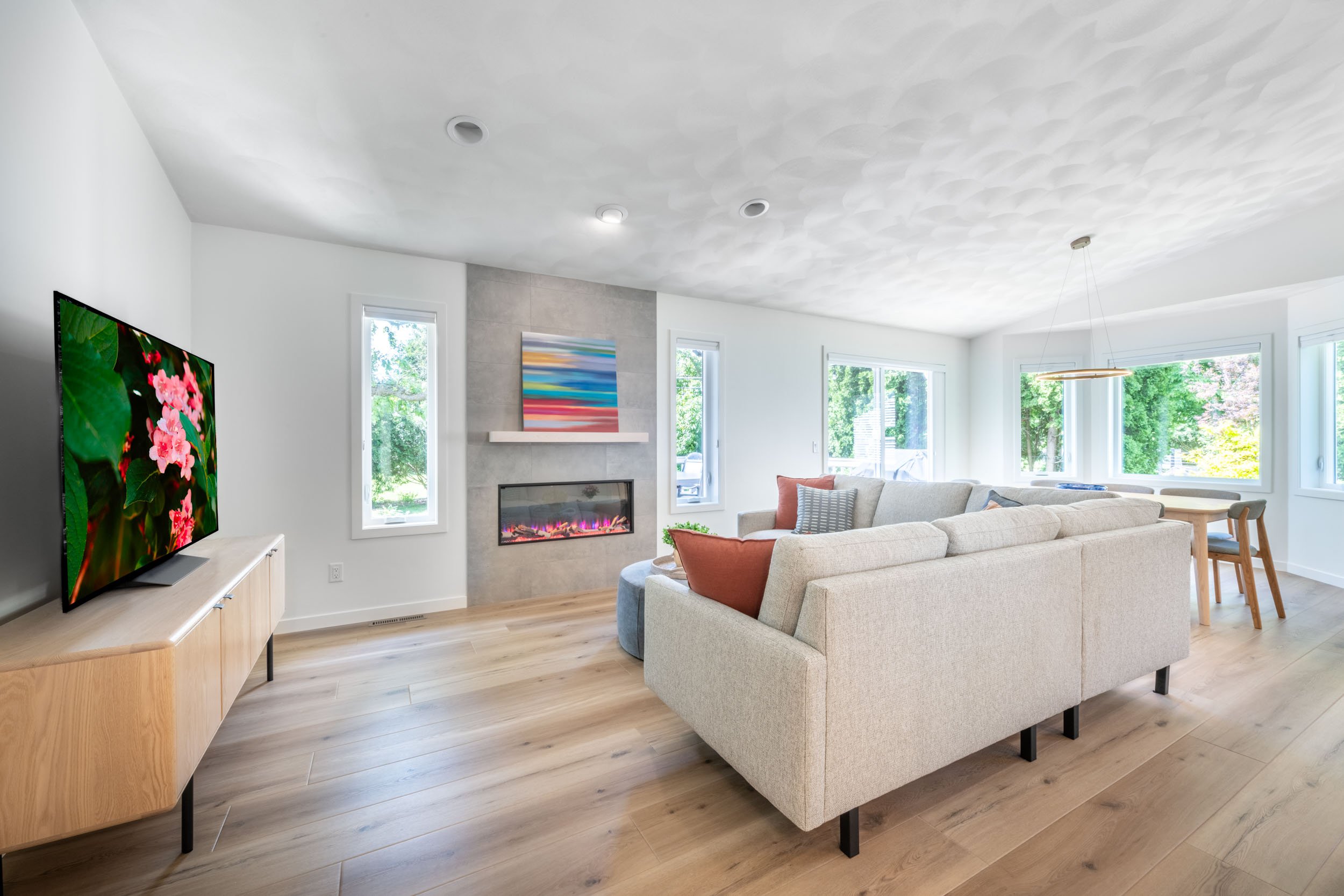Wide angle view of the living room, featuring the Heat n Glo electric fireplace and Trends In Ceramic tile surround, with the dining room in the distance.