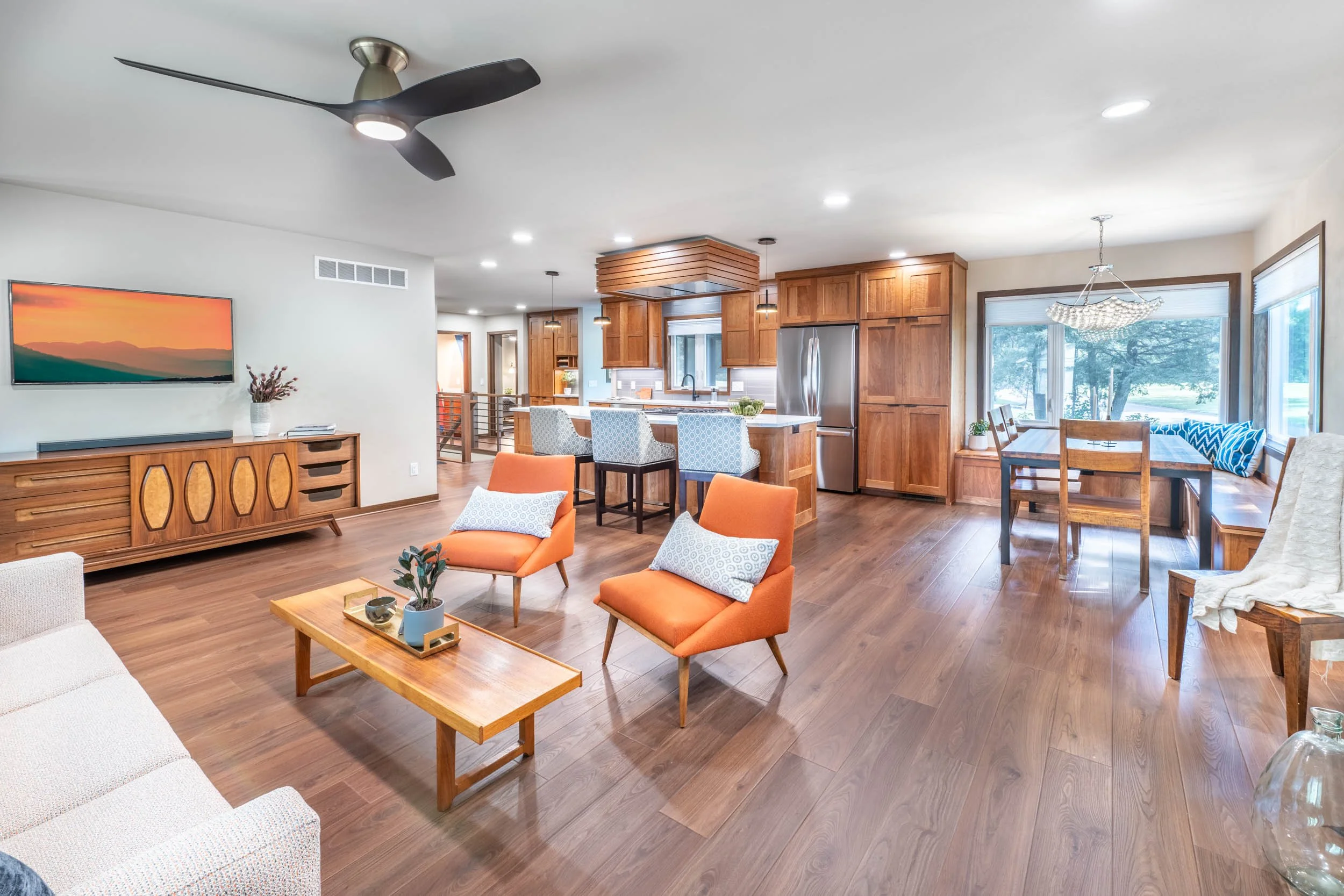 A open concept ranch home with dark wood floors, medium cherry cabinets, and large dining room windows.