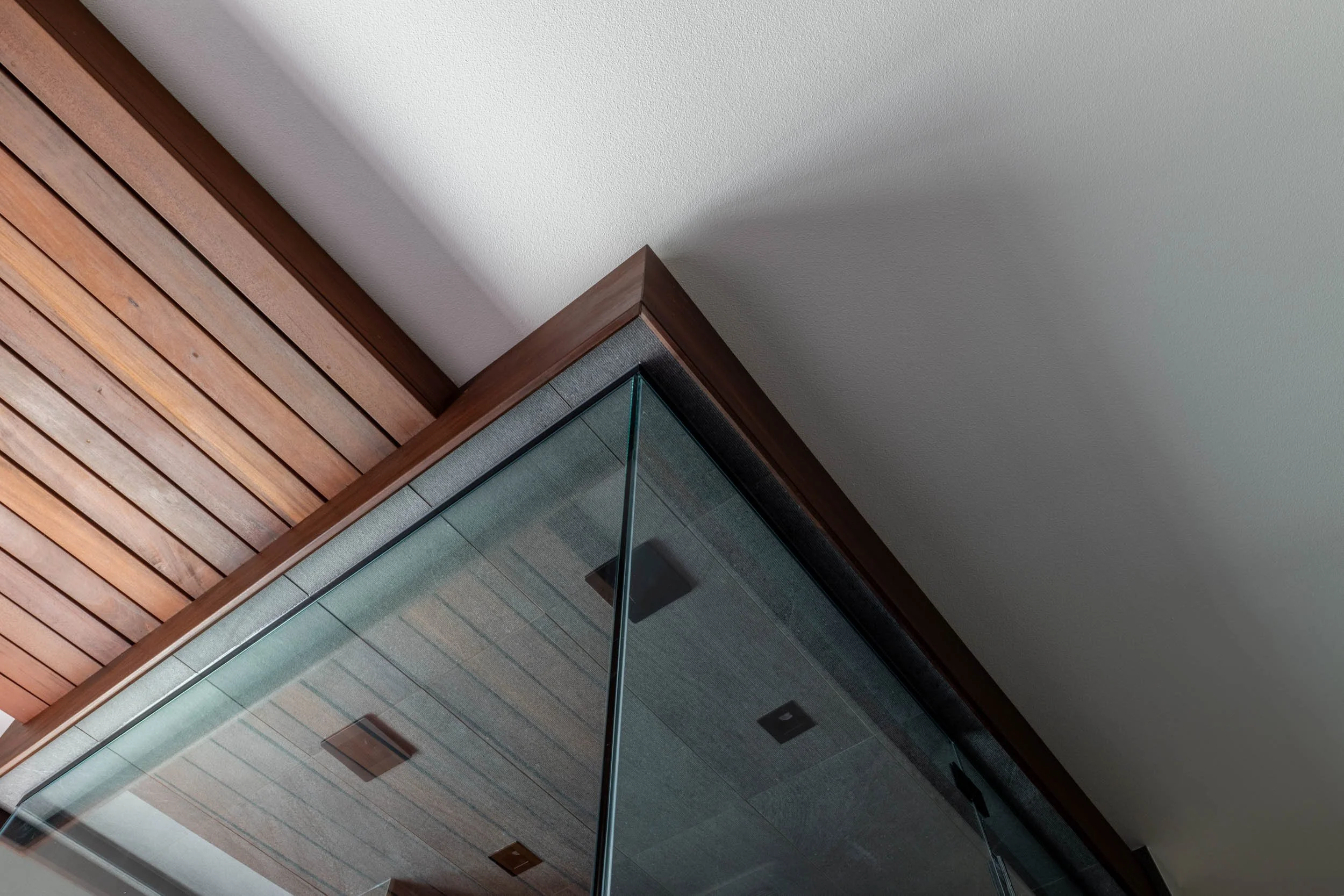 A detail view of the shower glass, teak connection, and teak detail