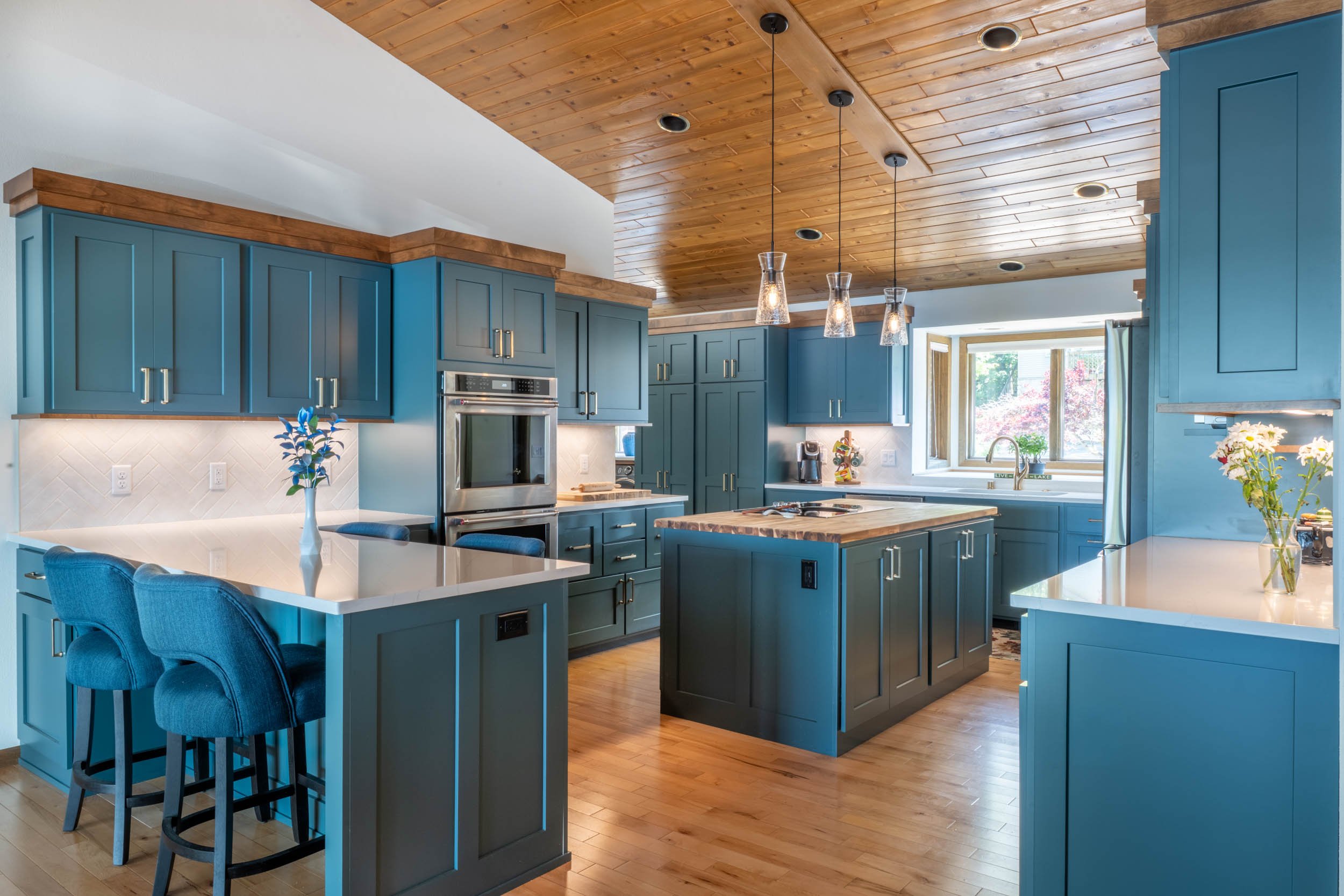 View of the recently remodeled kitchen showing blue cabinetry, white quartz perimeter countertops with a kitchen island with butcher block countertops.