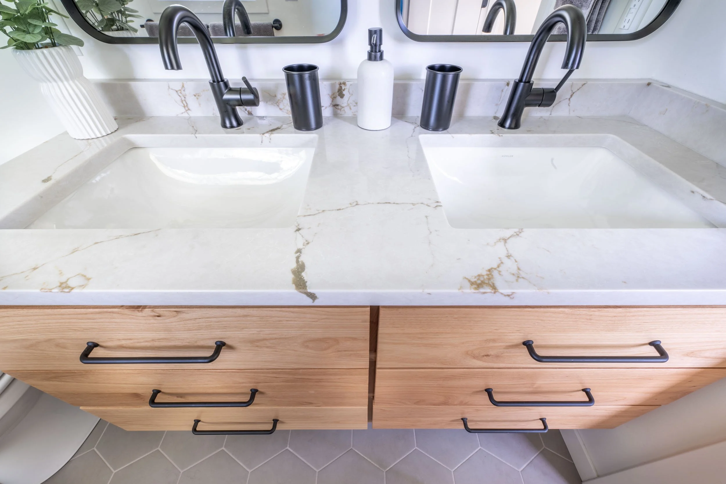 Close up view of the floating vanity, featuring the Silestone quartz countertop, and the matte black Delta faucets