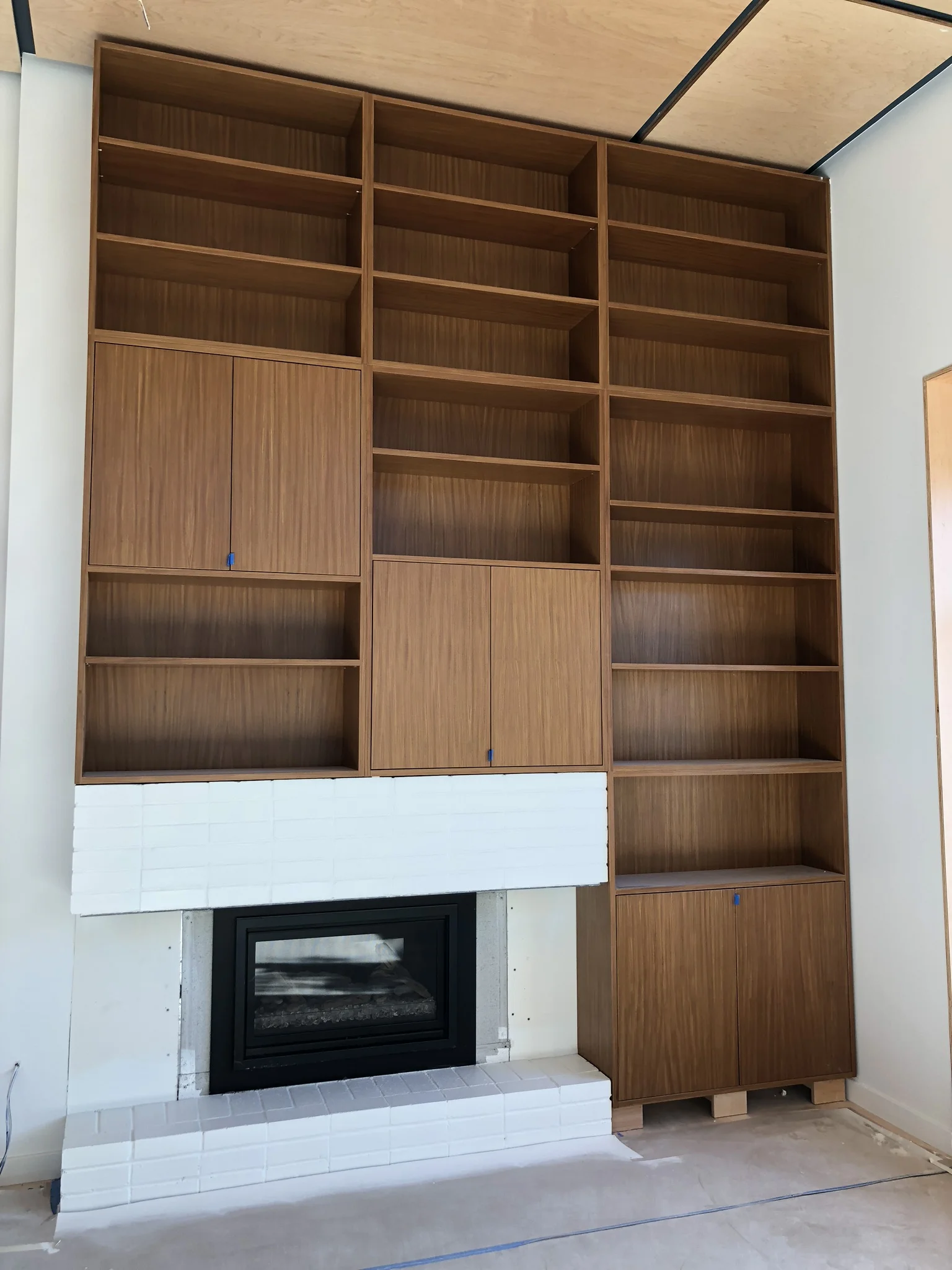 beautiful bookcase in afromosia veneer by Laak Woodworks and a white painted fireplace