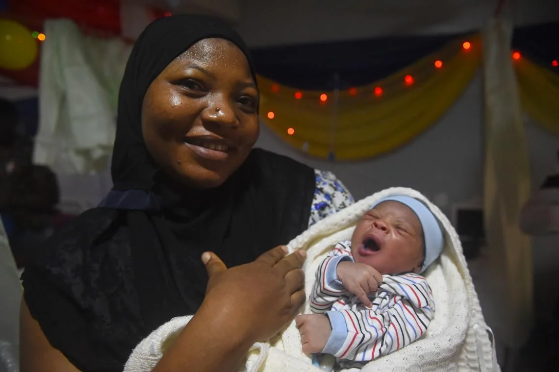 Lagos, Nigeria, 12:00 am: Basirat Adegbesan soothes her newborn son, 3.7kg (8.1lbs.), at Lagos Island Maternity Hospital. “Though I was not expecting it today, God made me to deliver the first baby of the year,” Basirat says. He is the fourth child of Basirat and her partner, Wasiu. With mobile phones, UNICEF and partners reach new mothers throughout Lagos state with text and voice messages in local dialects announcing such things as maternal, newborn and child health weeks.