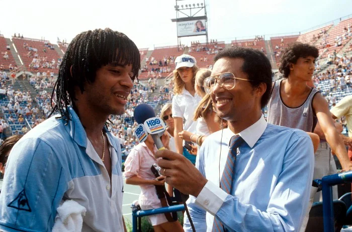 Arthur Ashe interviews Yannick Noah at the U.S. Open in 1983. Ashe discovered Noah at a 1970 exhibition at the Tennis Club de Yaoundé Cameroon, when the then 10-year-old kid started knocking back the black champion’s balls. Noah was born in France and brought back to Cameroon at a young age, but Ashe phoned Philippe Chartrier, president of both the Fédération Française de Tennis and the ITF to find him sponsorship.