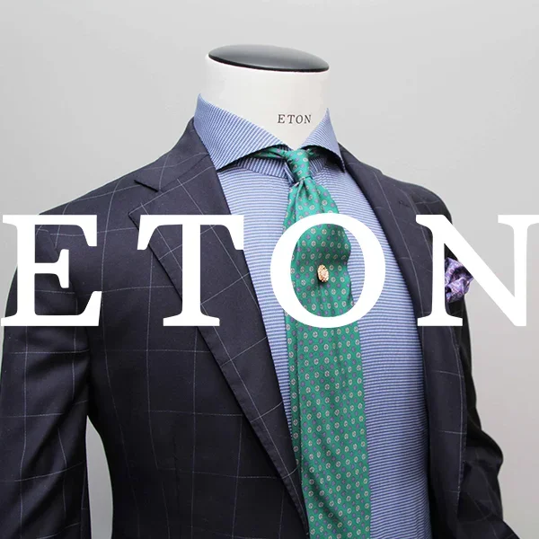 a navy blue patterned blazer paired with a blue striped shirt and a green patterned tie from Eton.