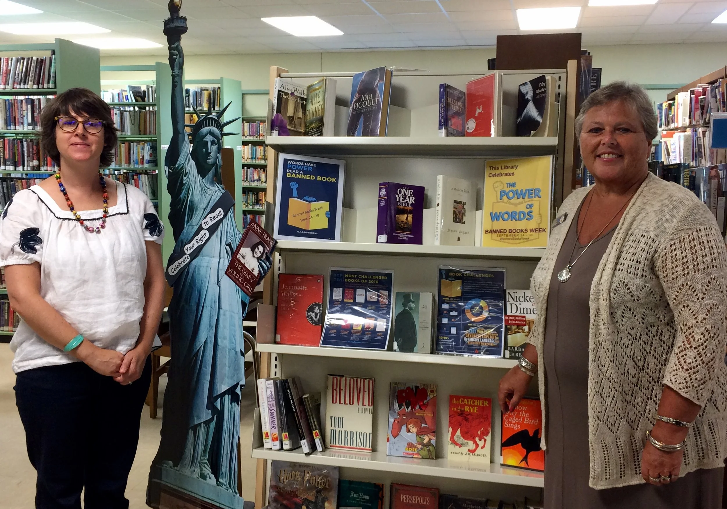 Librarian Charle Ricci (left) and Connie Campbell, Vice President, BB&T, review books on the new book display shelf that the BB&T Lighthouse Project sponsored.