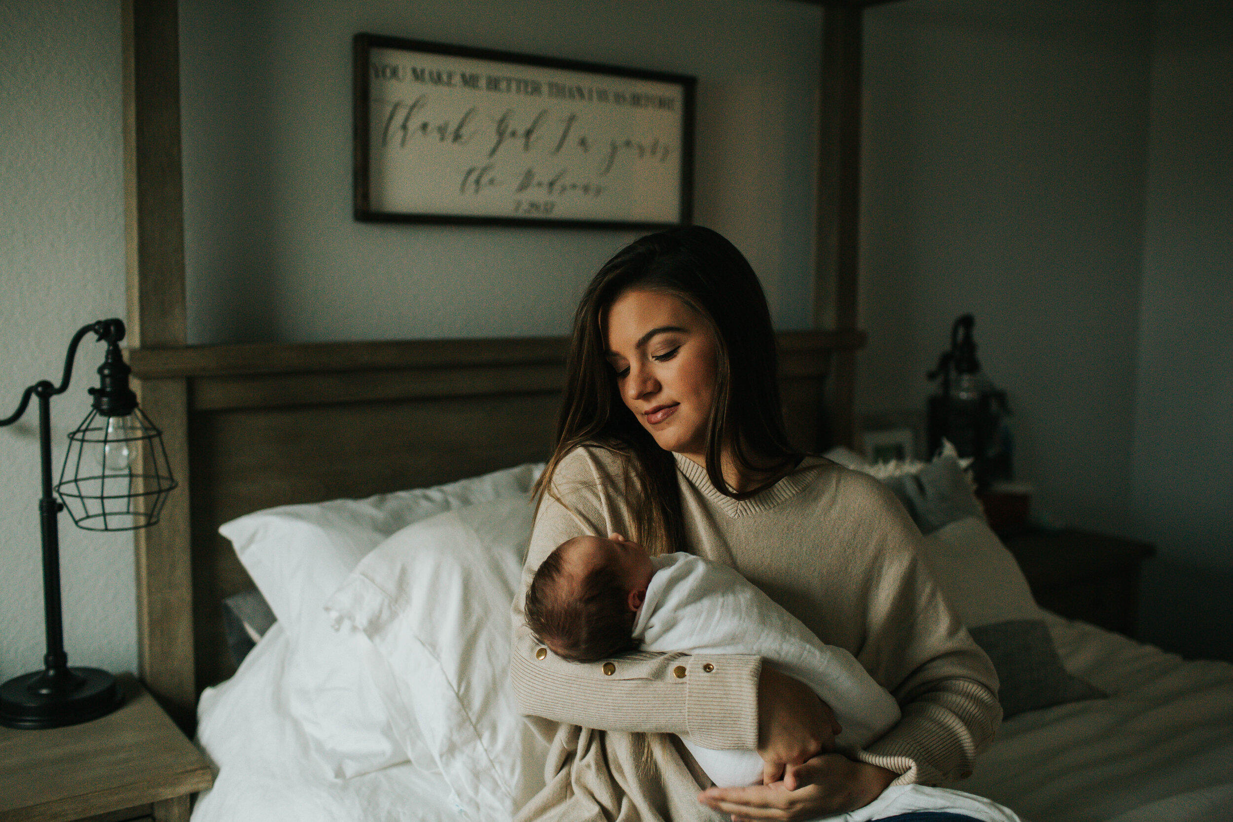 mom holding newborn baby on bed