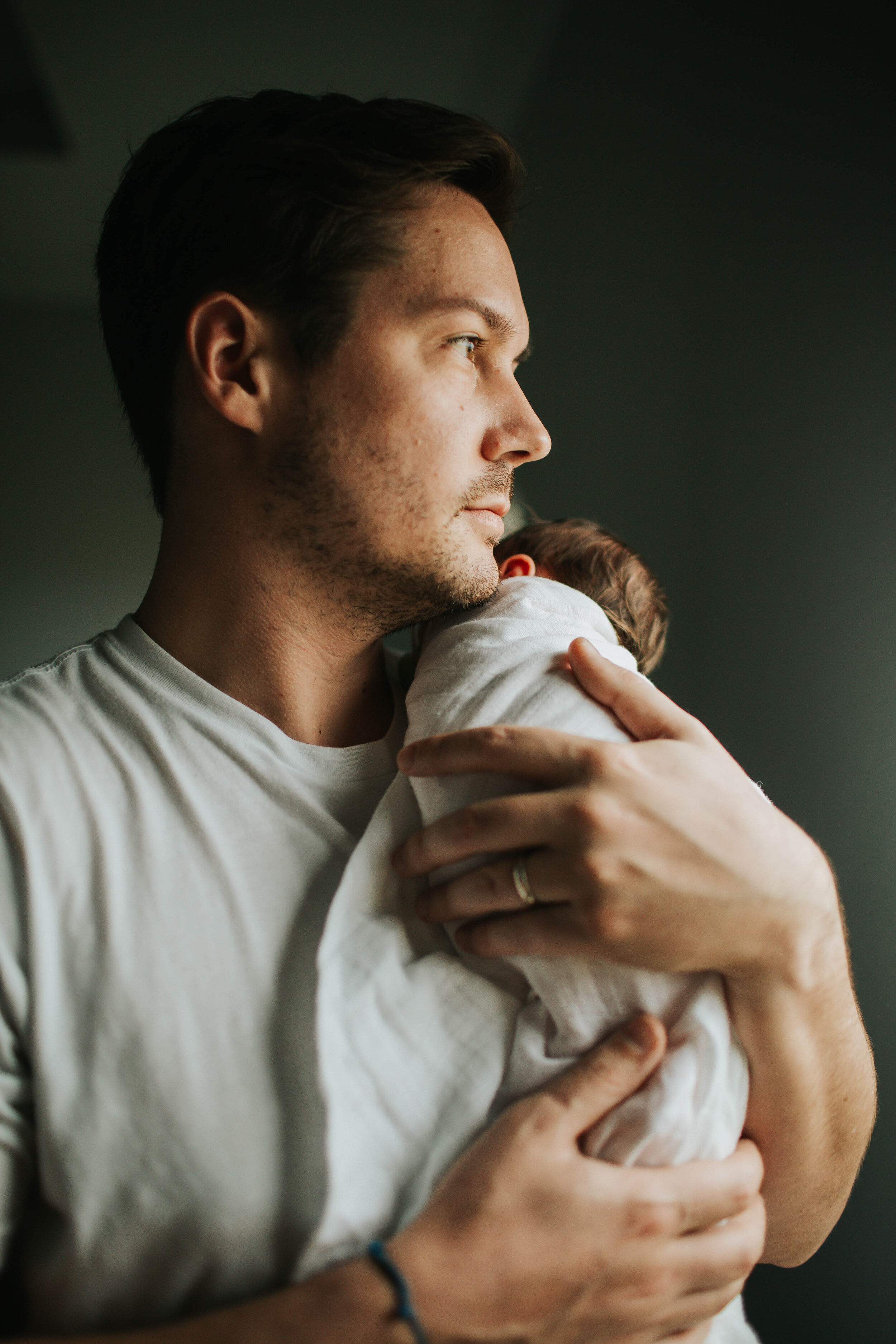 dad holding newborn baby girl looking out window