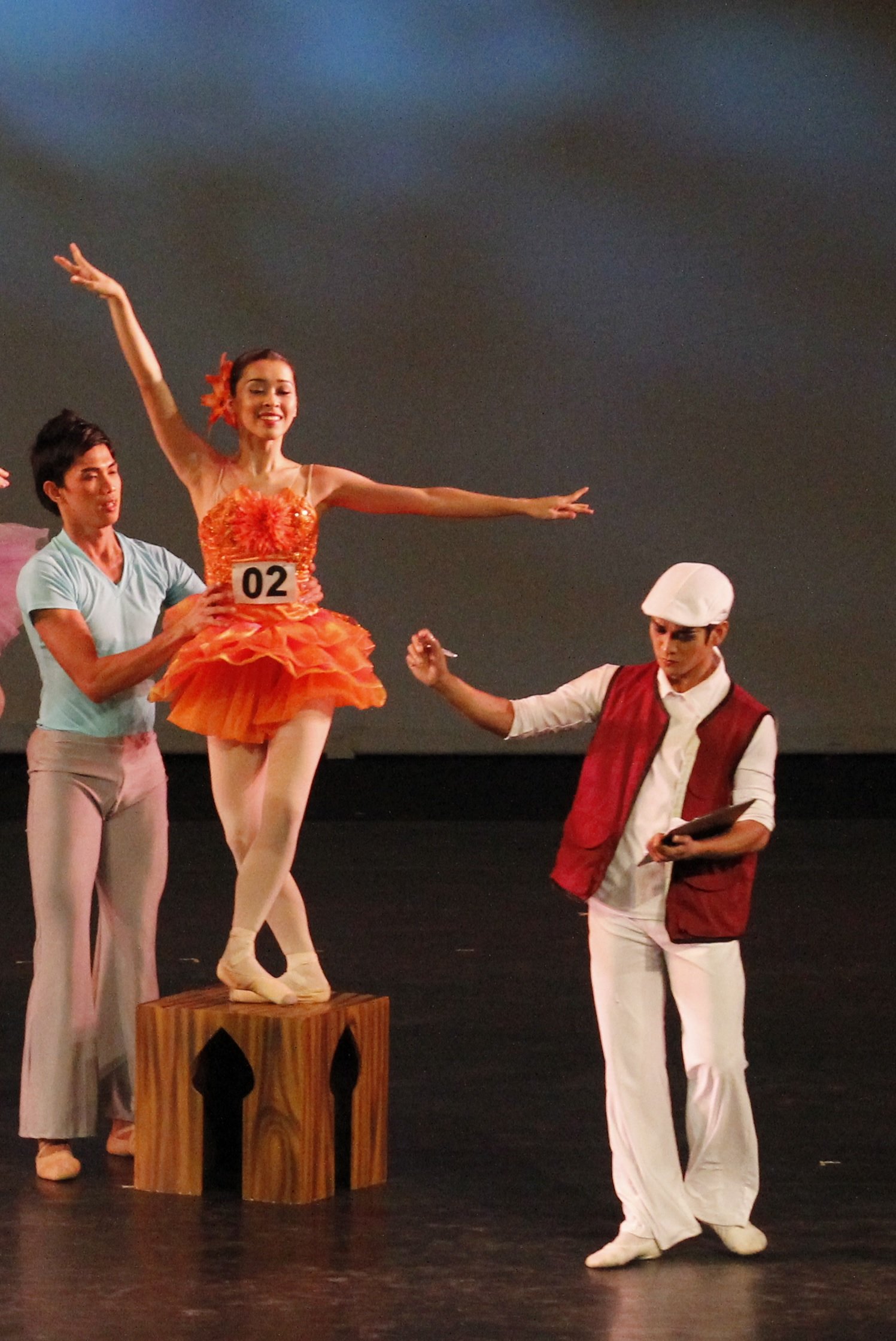    Rudy De Dios as the casting agent in  Sinderela  (2012) assesses one of the hopefuls played by Marika Capati – in an attractive salmon tutu – if she will make the cut, as she is assisted by Harold Salgado.  Sinderela  choreographer Hazel Sabas-Gow