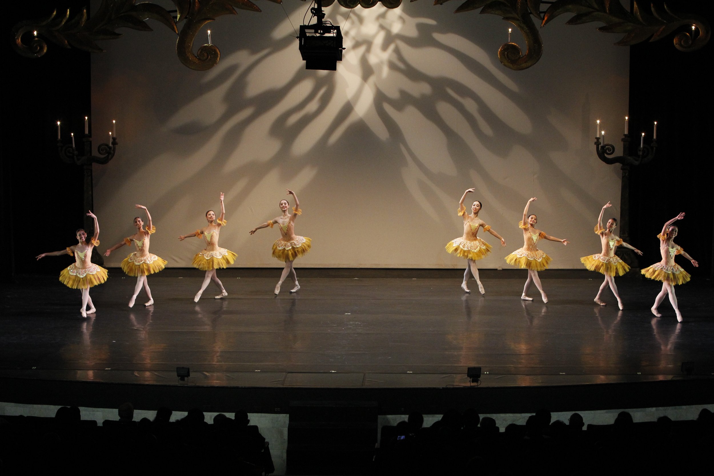    Ballerinas in yellow orange tutus stand out on the darkened stage as they dance a variation from the romantic ballet  Paquita , part of the program in  BM 2.0  (2015). Photo by Kurt Alvarez   