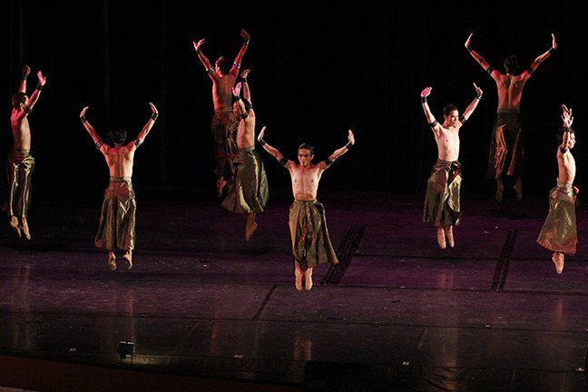    The all-male ensemble in Augustus “Bam” Damian III’s  Reconfigured  – part of the repertoire of Ballet &amp; Ballads (2013) – is caught in mid-air in this shot, sporting olive green bottoms with side slits that flip and flare as they move. Photo b
